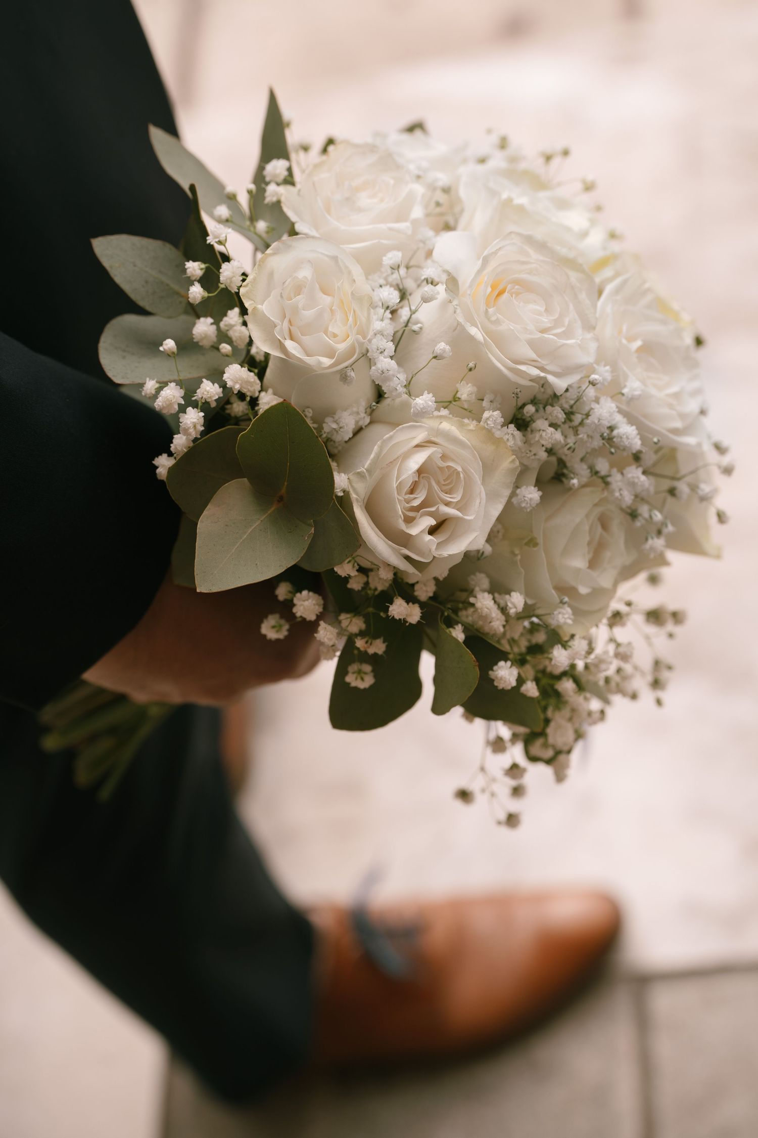 Close-up of a delicate white rose and baby's breath wedding bouquet.