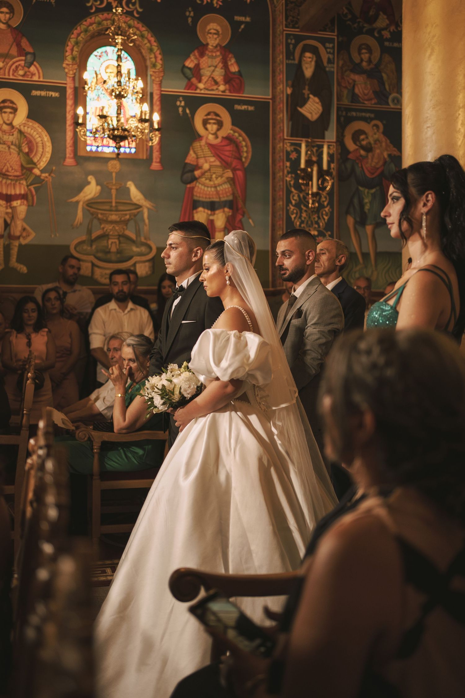 Orthodox Christian wedding ceremony in a traditional church with ornate religious icons and decorative elements.