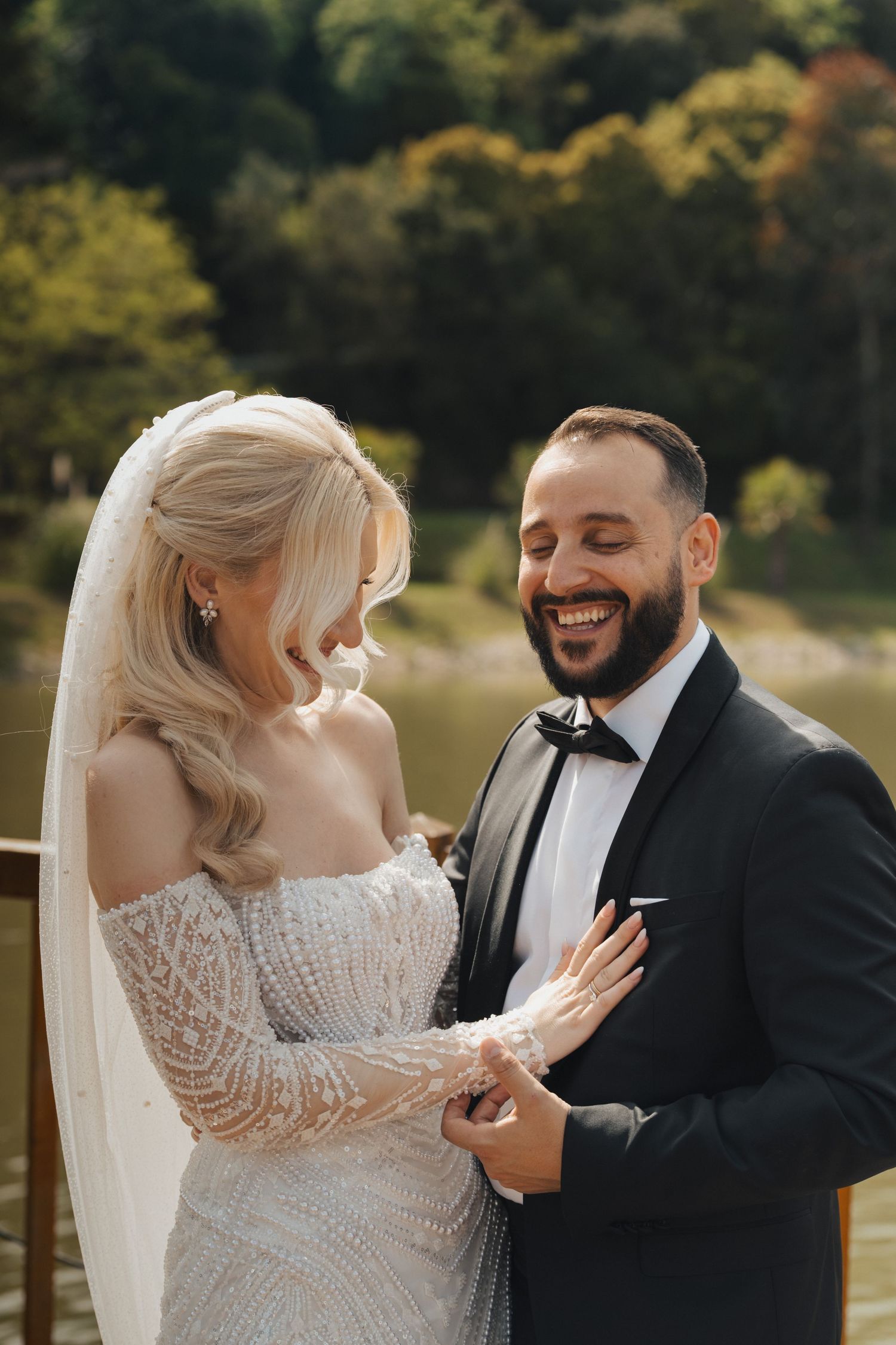 Intimate wedding portrait showing a couple in a lace dress and black suit sharing joyful moments outdoors.