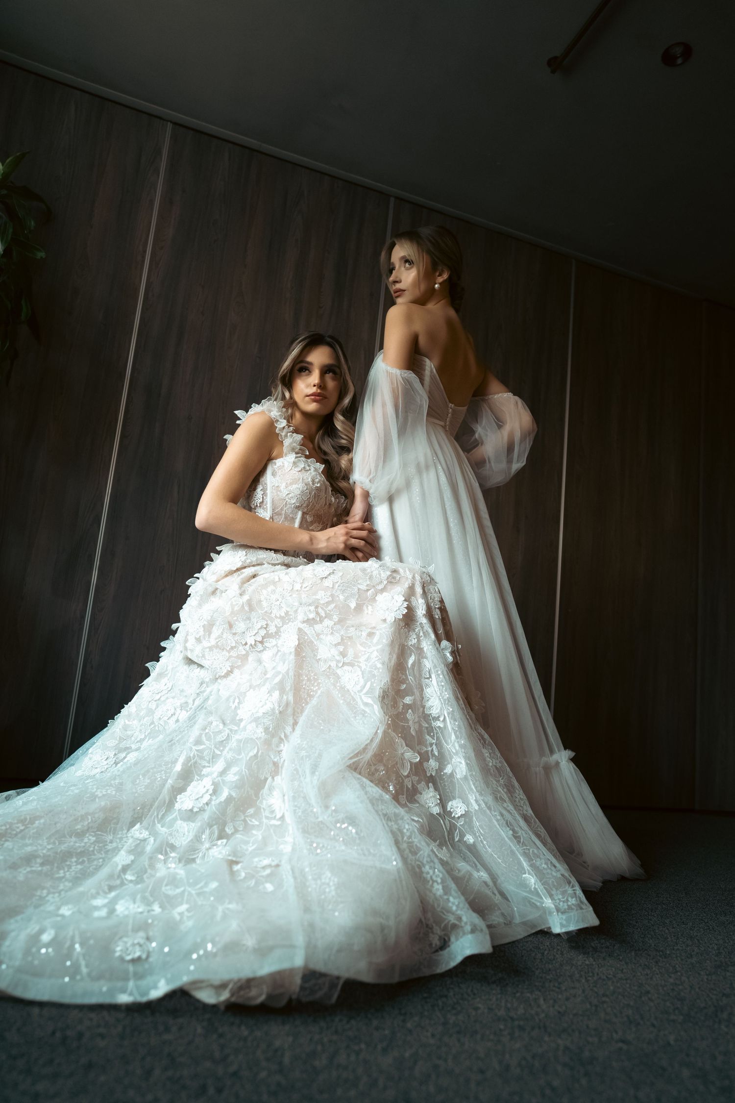 Elegant bridal gown with detailed lace overlay photographed in dim lighting.