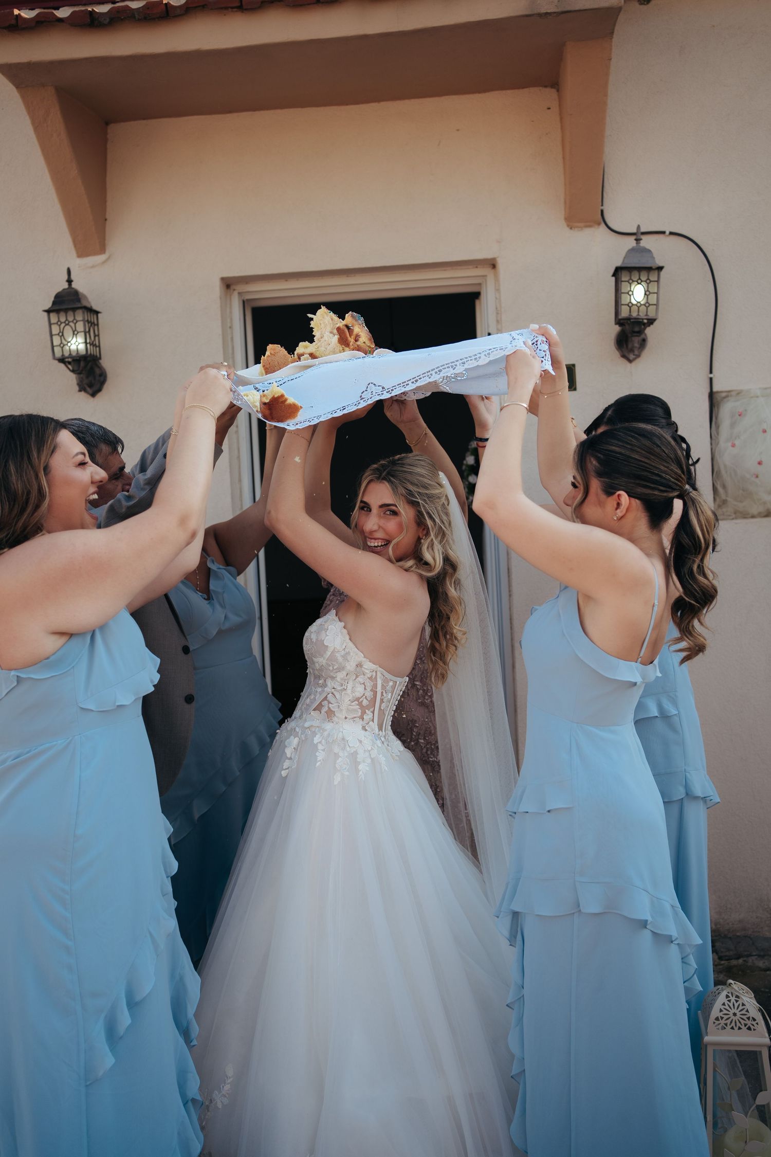 A group of bridesmaids in light blue dresses celebrate with a bride in a white ball gown during a wedding celebration.