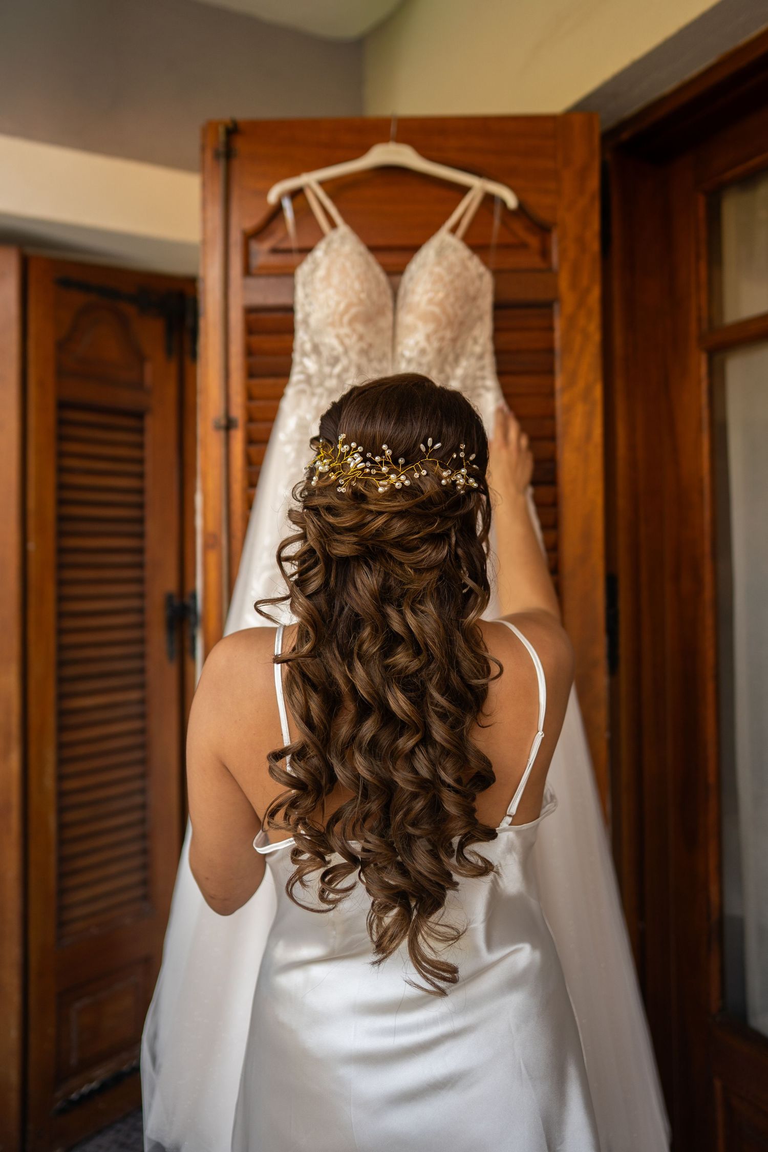 Four views of an elegant white wedding dress hanging with a curled hairstyle visible in preparation for a ceremony.