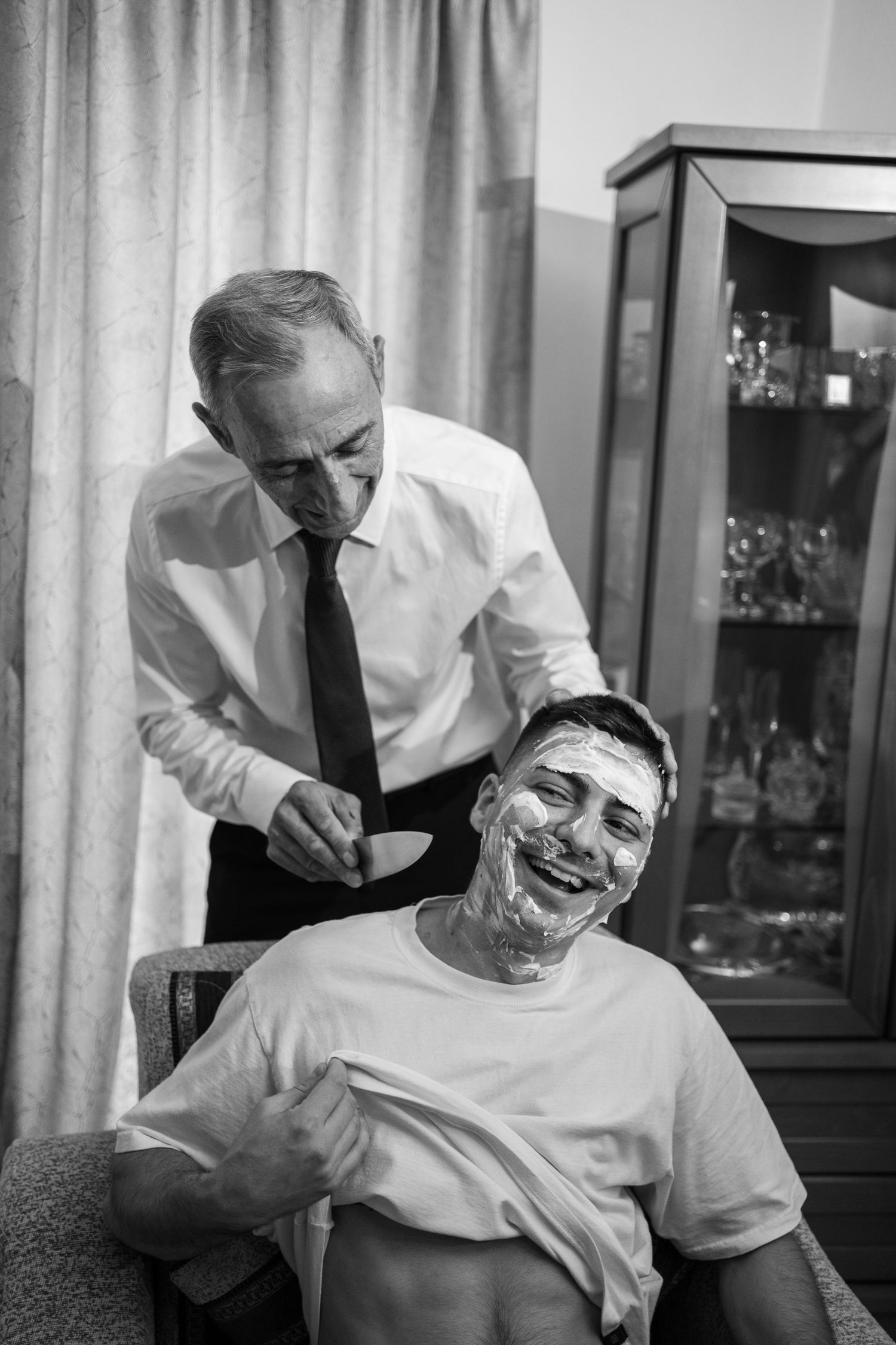 Black and white sequence showing a man getting a shaving cream facial treatment at a barbershop.