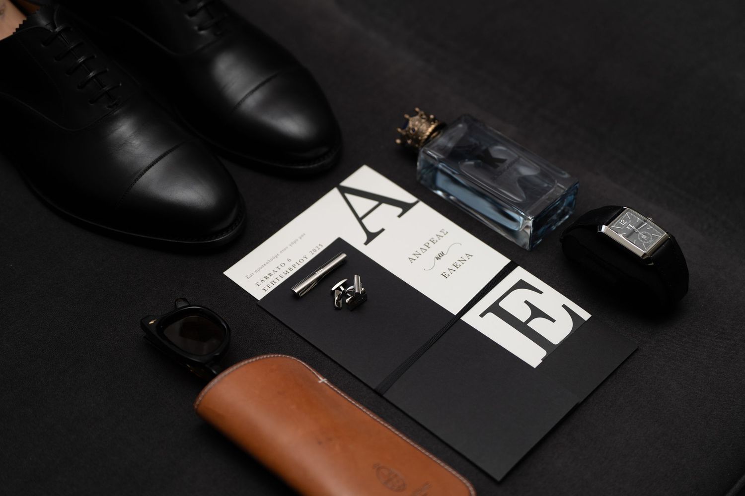 Stylish black leather boots and accessories arranged in a dark moody composition against black background.