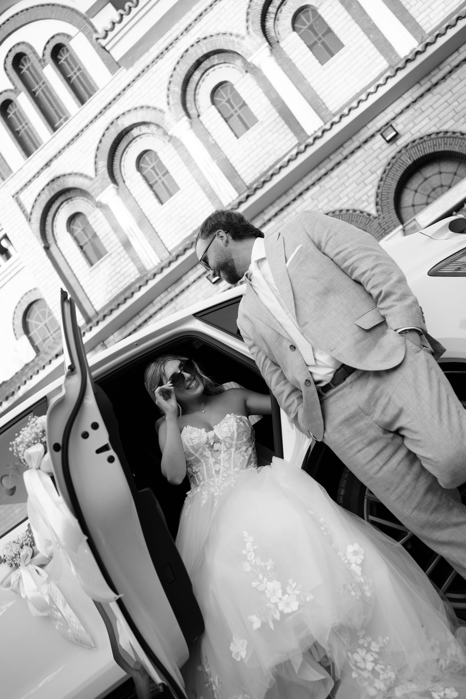 Black and white wedding photos showing couple posing against architectural backdrop.