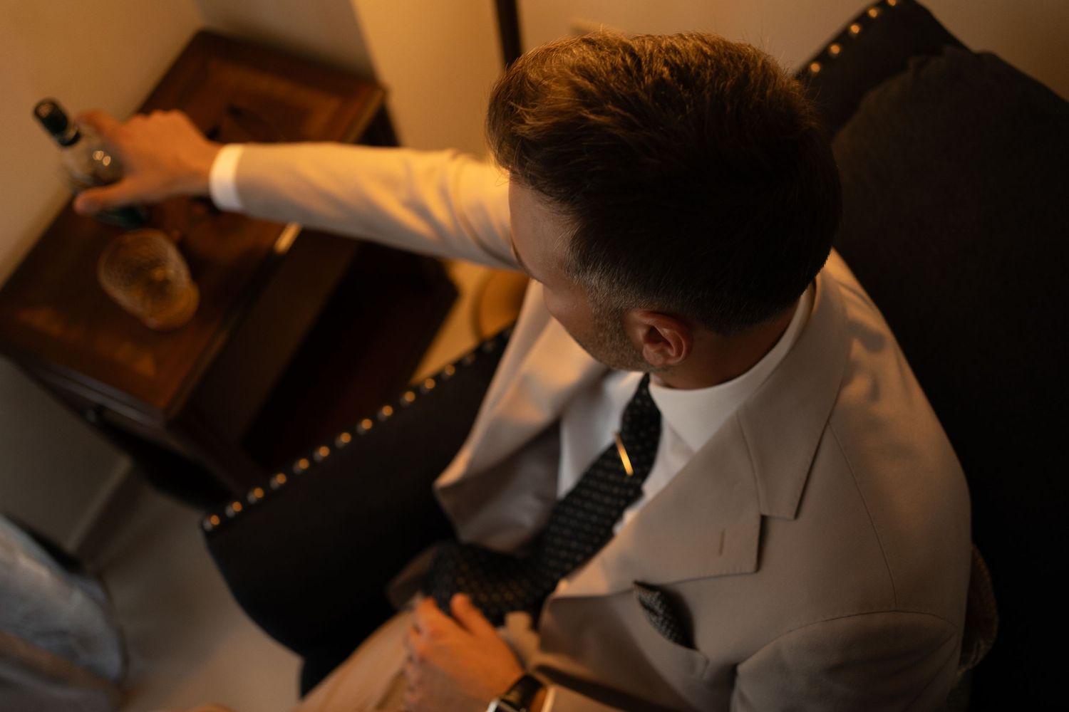 Professional signing paperwork at a wooden desk with documents and a pen in a dimly lit office setting.