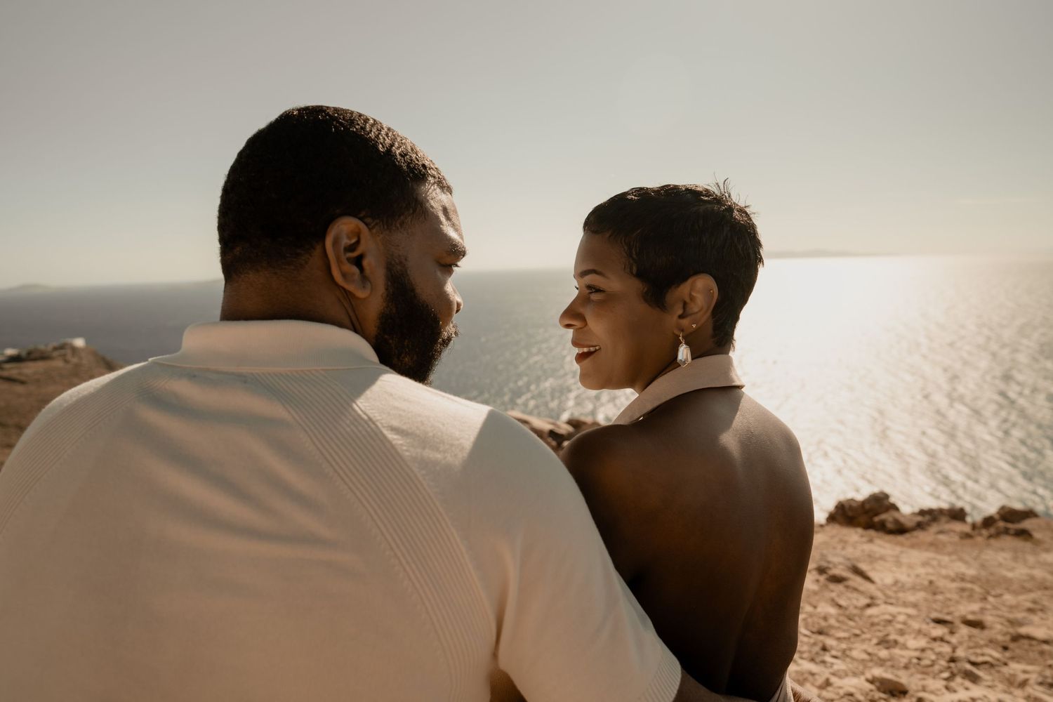 Silhouetted couple sharing an intimate moment against a bright coastal backdrop celebrating their 20 years together.