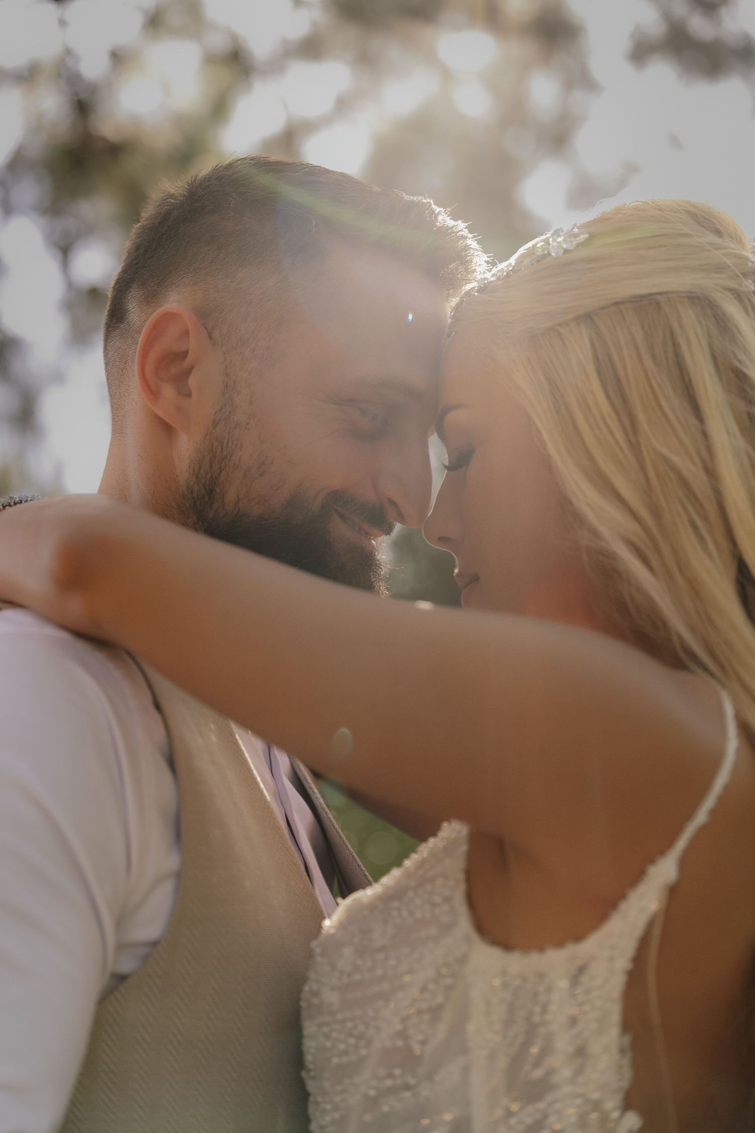 Sun-drenched wedding portrait capturing intimate moment between couple in natural lighting.