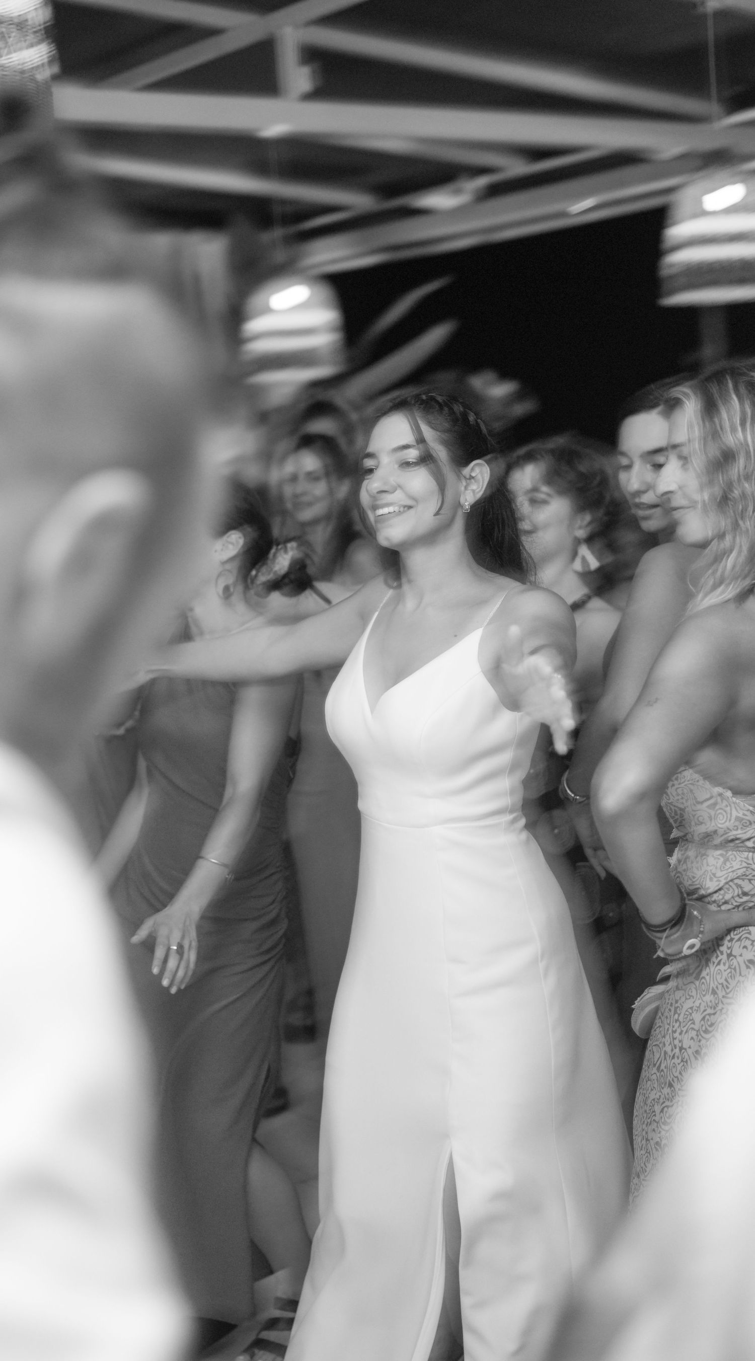 Wedding party dancing together in a joyful celebration at an indoor reception venue.
