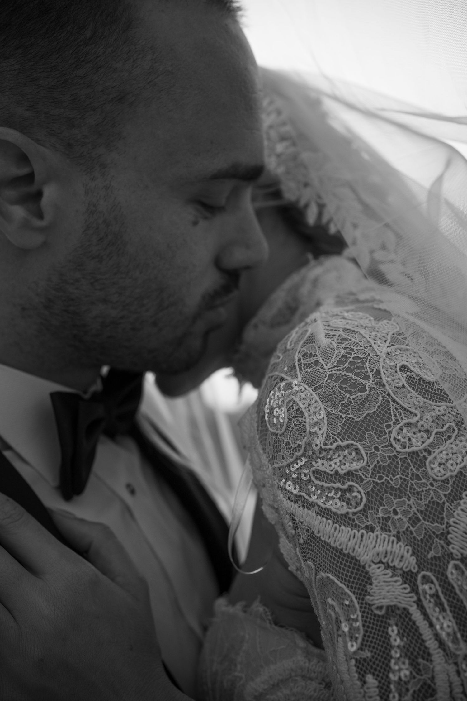 Black and white close-up of intricate lace wedding dress details.
