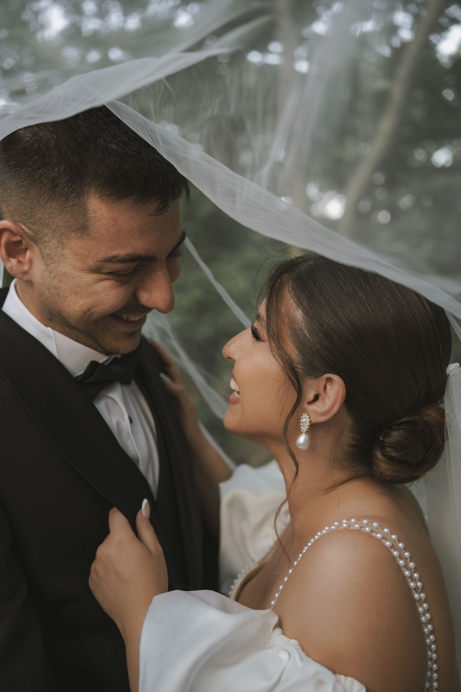 Intimate wedding portrait showing tender moment between couple under veil.