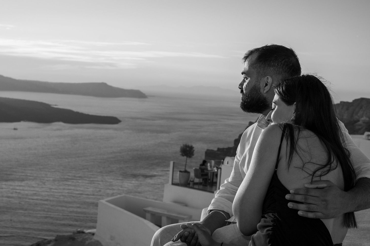 Couple sharing intimate moment overlooking Mediterranean Sea at sunset in Santorini greece