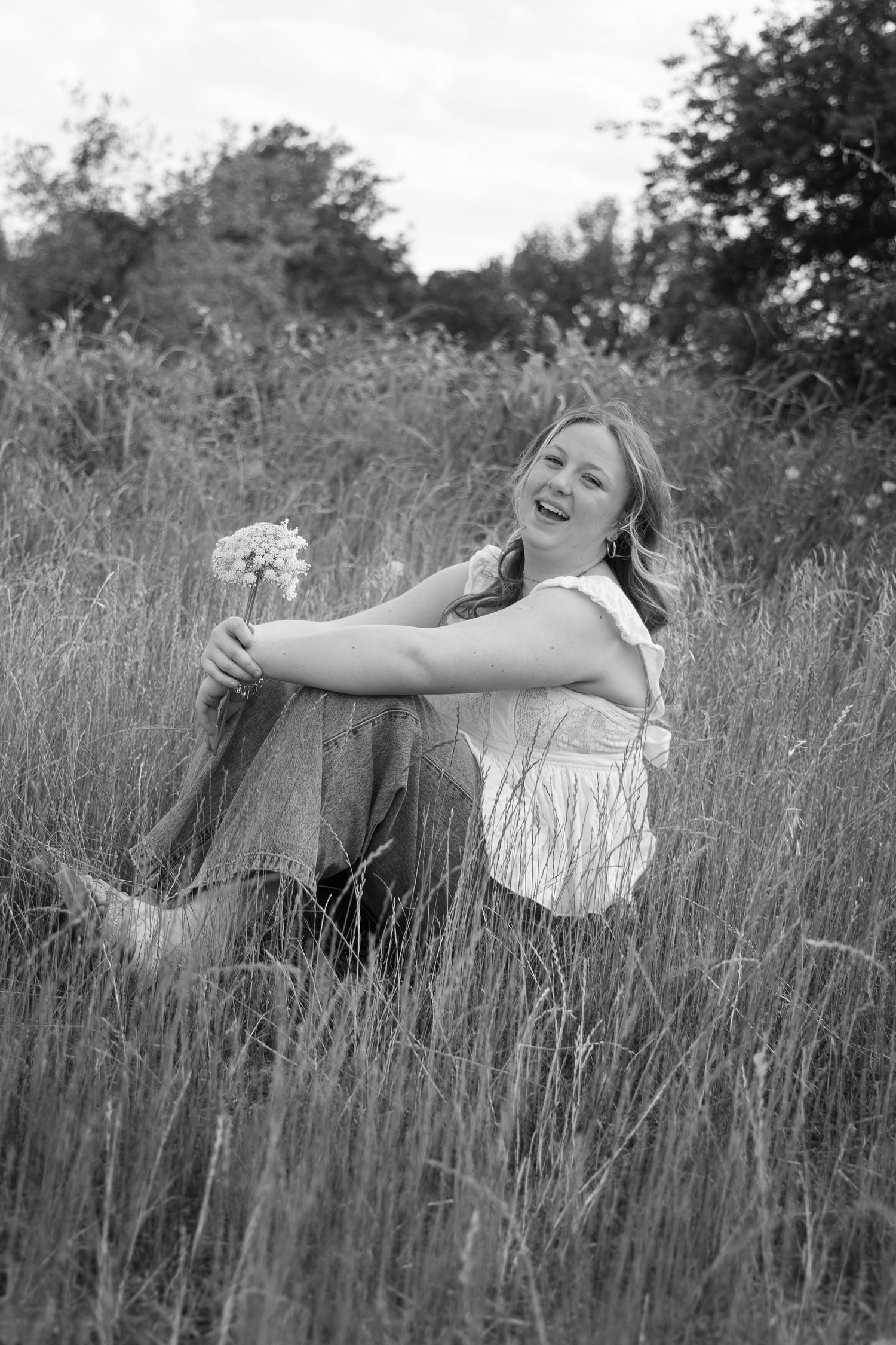 A black and white portrait shows someone frolicking in a field of tall grass.