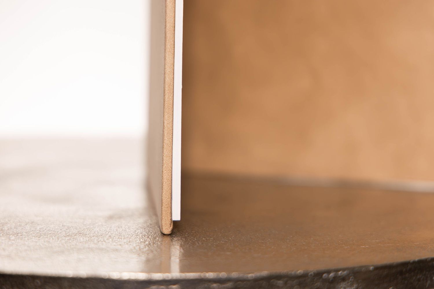 Close-up of a wooden panel standing upright on a smooth metallic surface with a warm beige background.