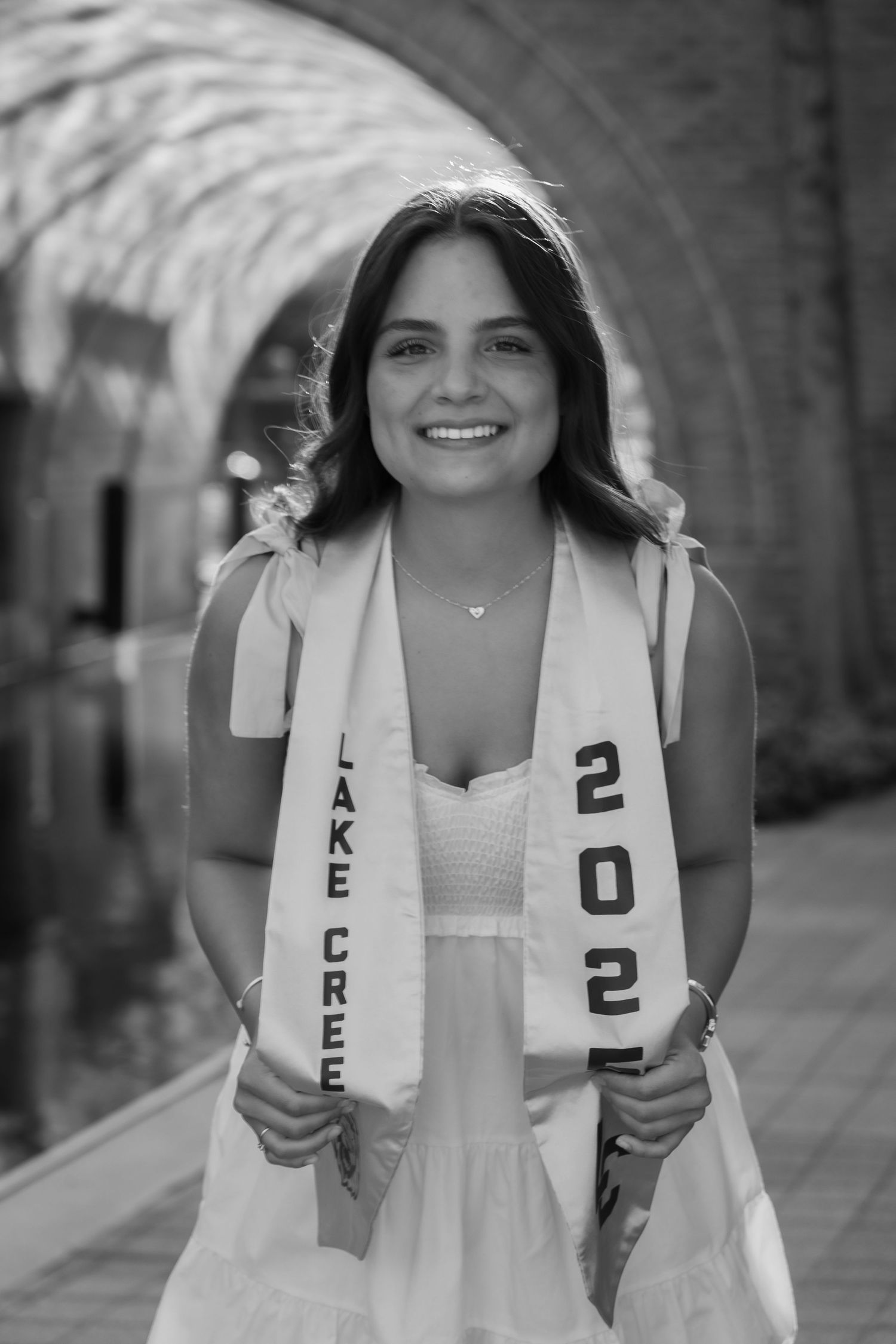Collection of senior year photos showing graduate posing in white dress and graduation stole with 2022 lettering.