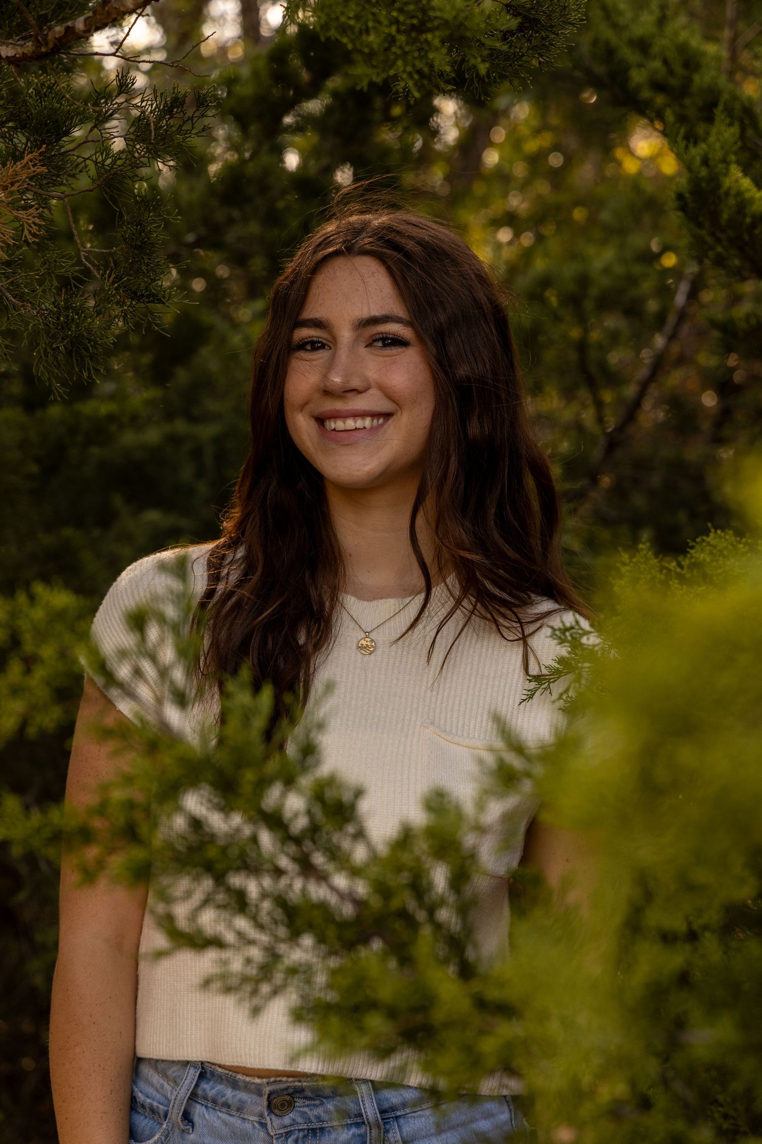 Portrait session in a lush garden setting with natural golden hour lighting and white sweater outfit.