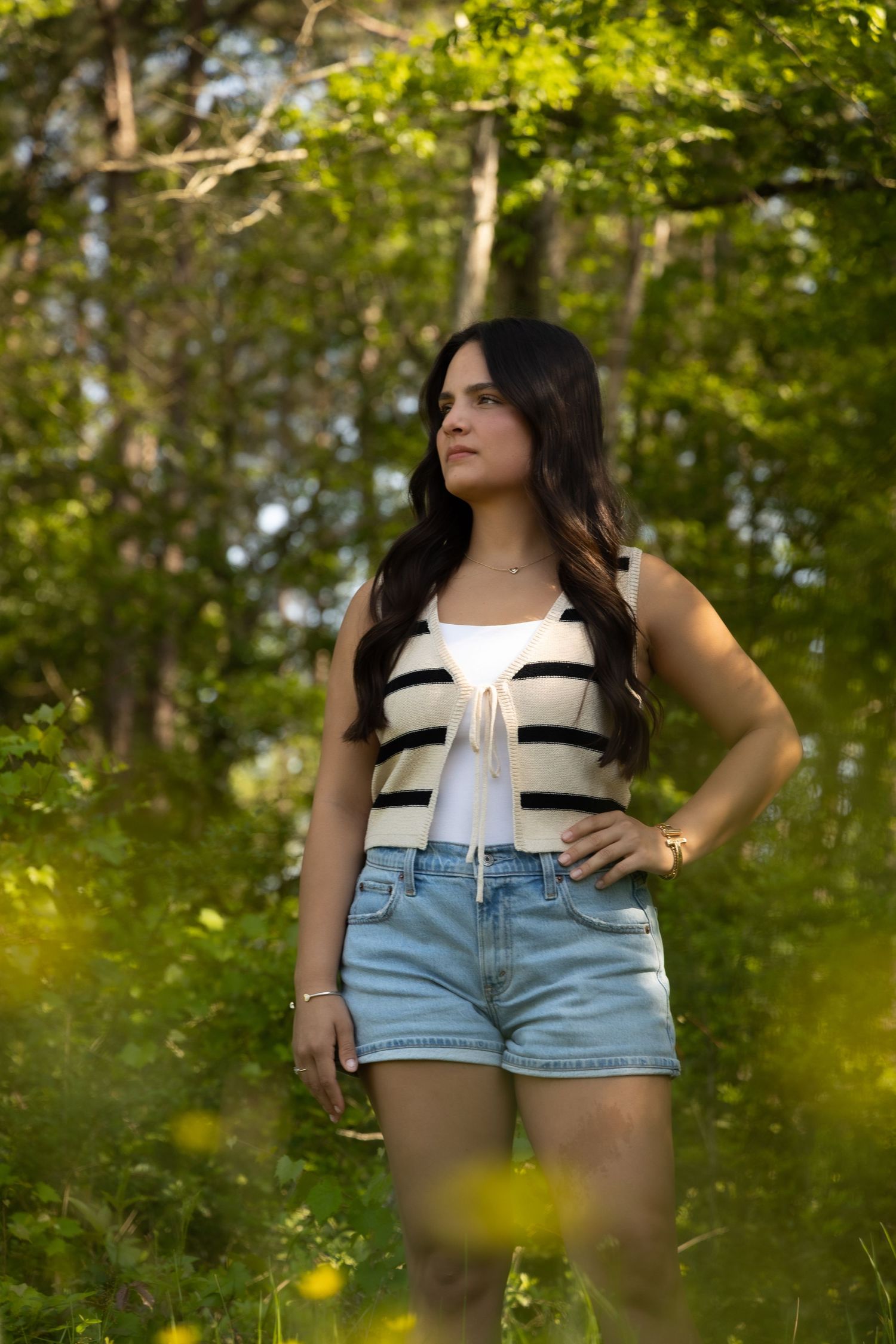 A summer portrait in a forest setting showcasing casual fashion with denim shorts and a striped top.