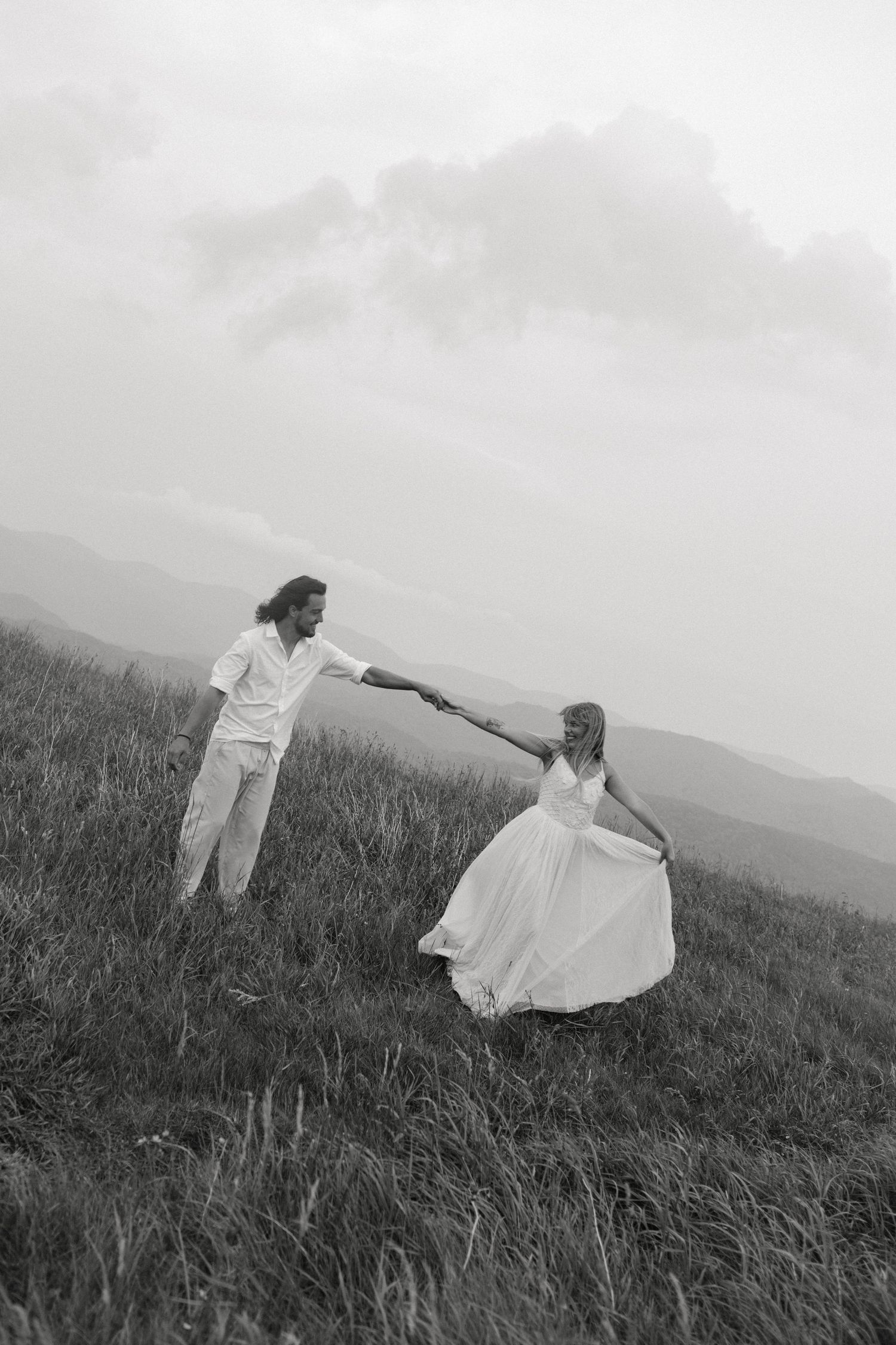 Four black and white photos show someone in a white dress moving gracefully through a misty mountain meadow.