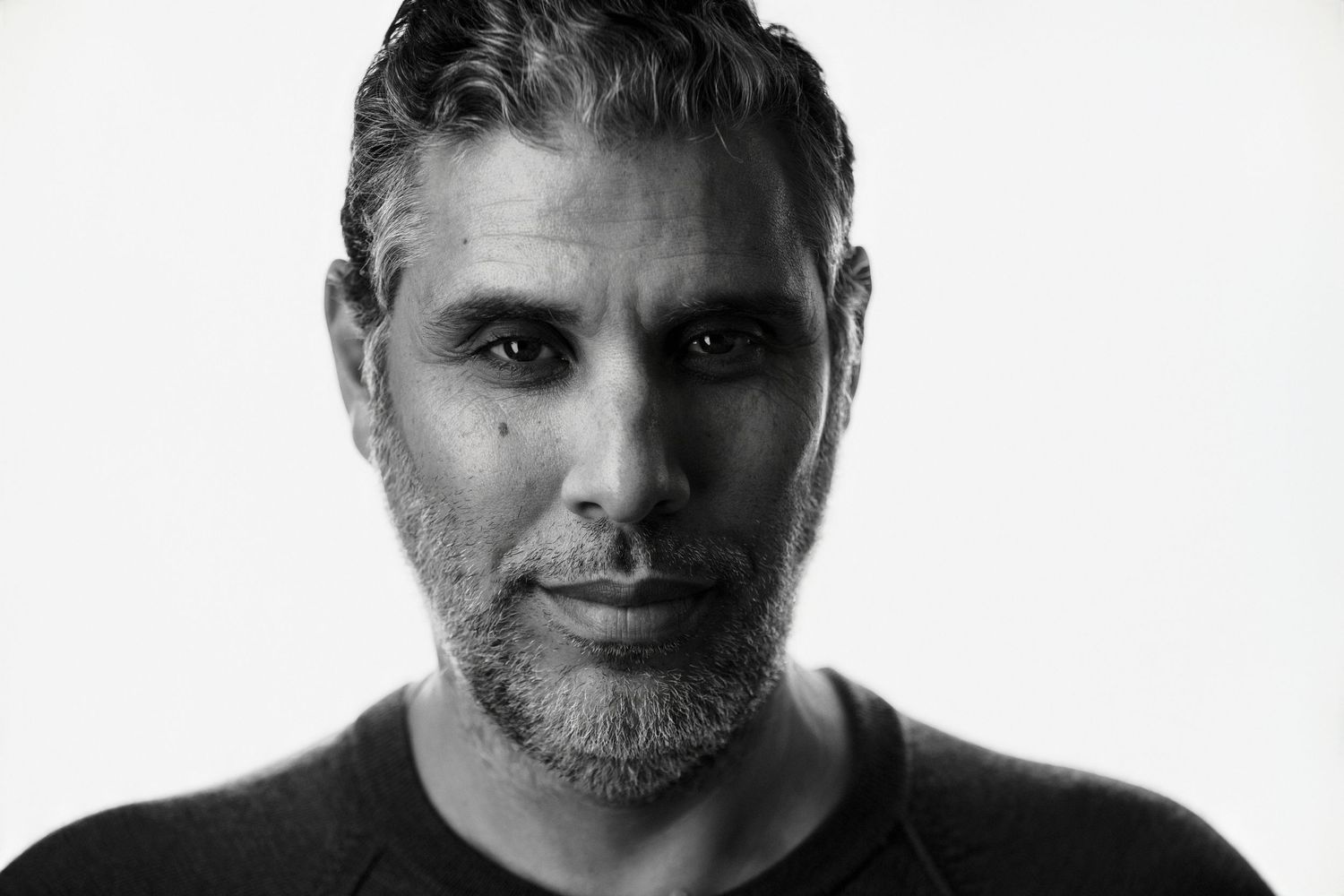 Black and white professional headshot of a man with salt-and-pepper hair and beard.
