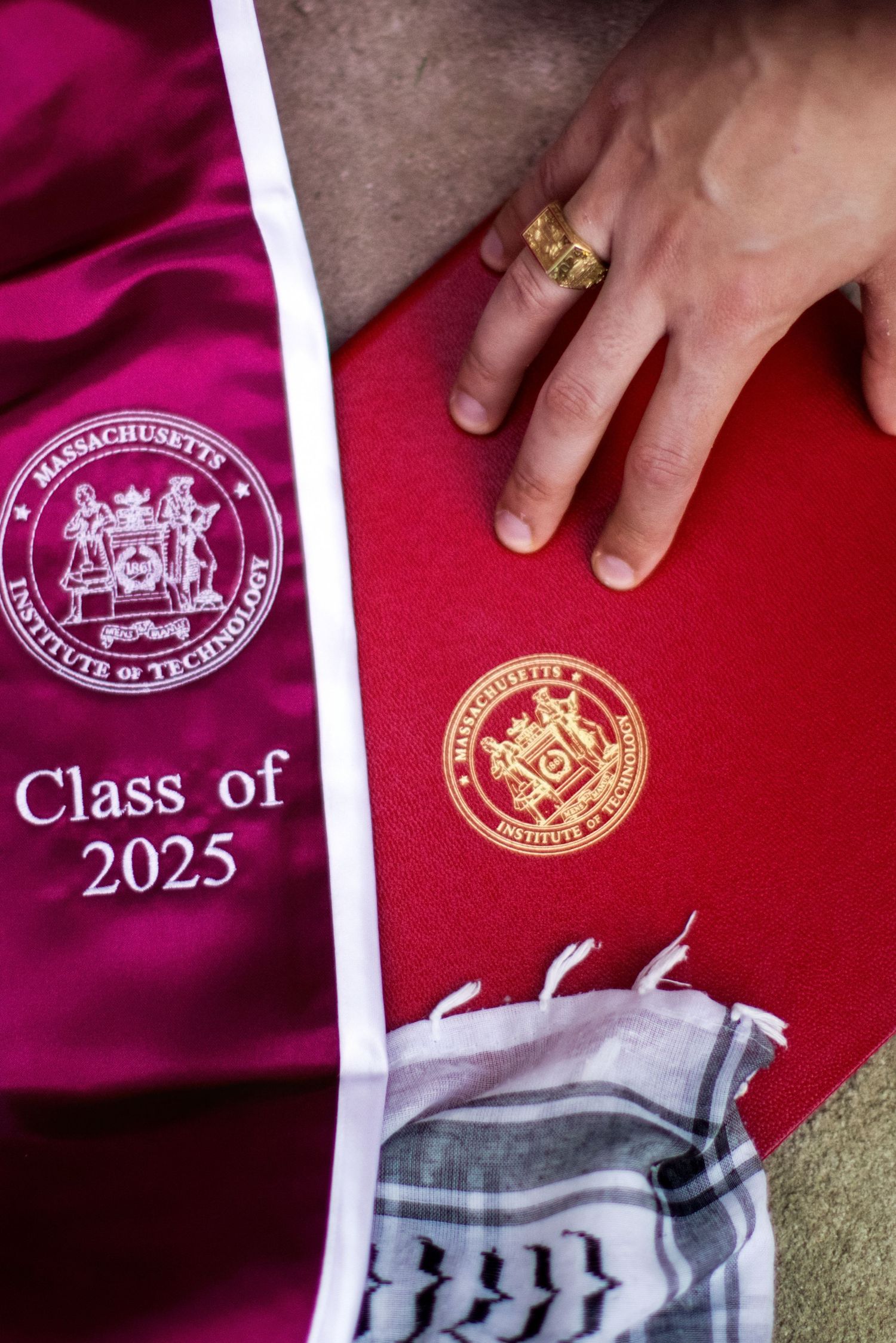 MIT Class of 2025 graduation sash and diploma with gold seal, held by a hand wearing a gold ring.