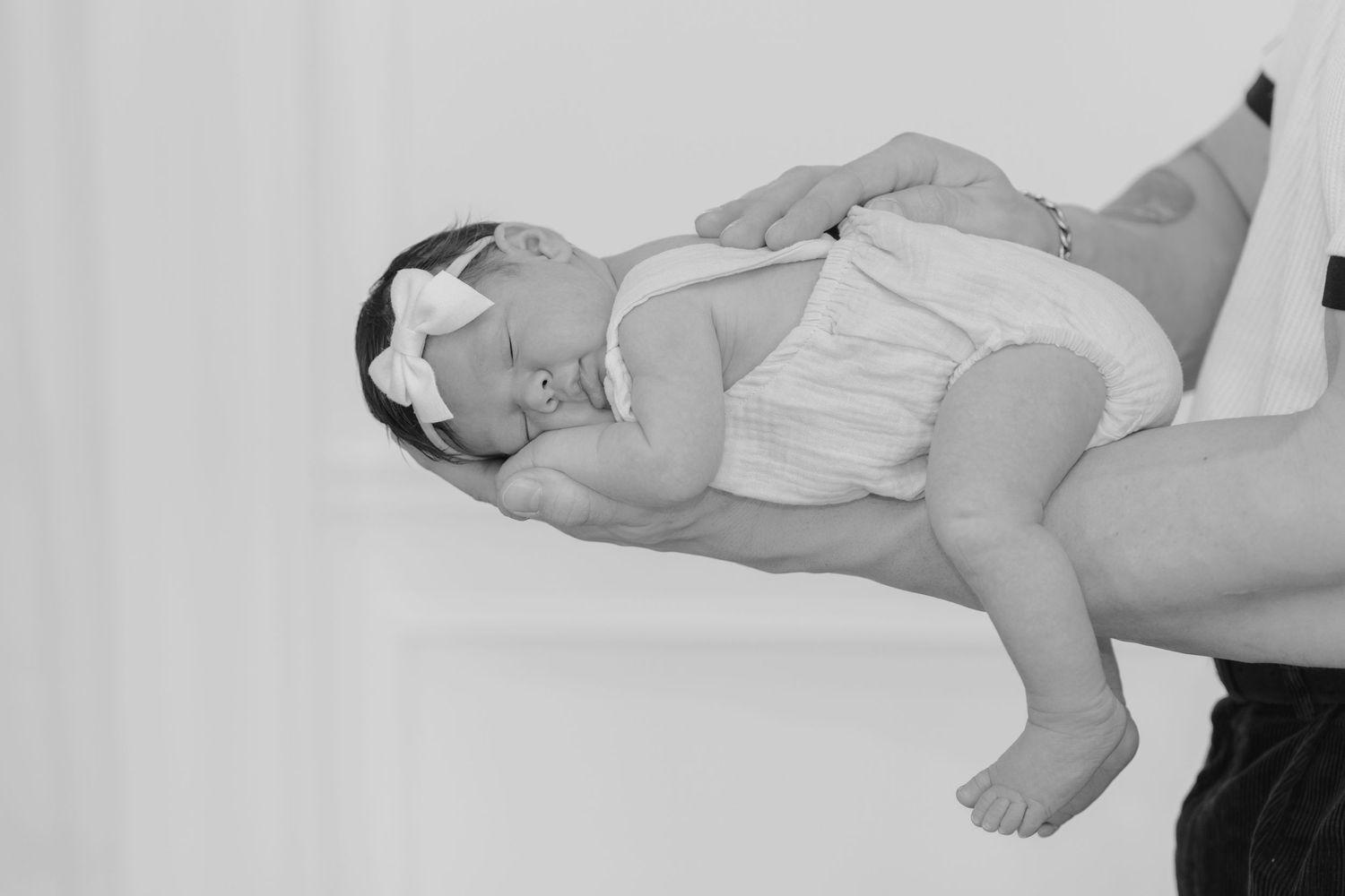 A black and white photo montage showing a sleeping baby in different positions on a white surface.