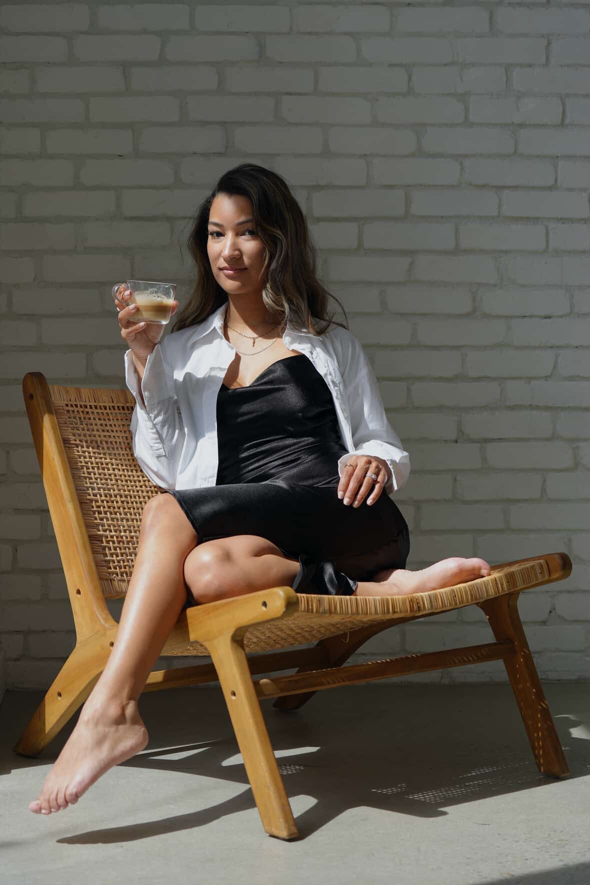 A sequence of photos showing someone in a black dress reclining on a wooden lounge chair against a white brick wall.