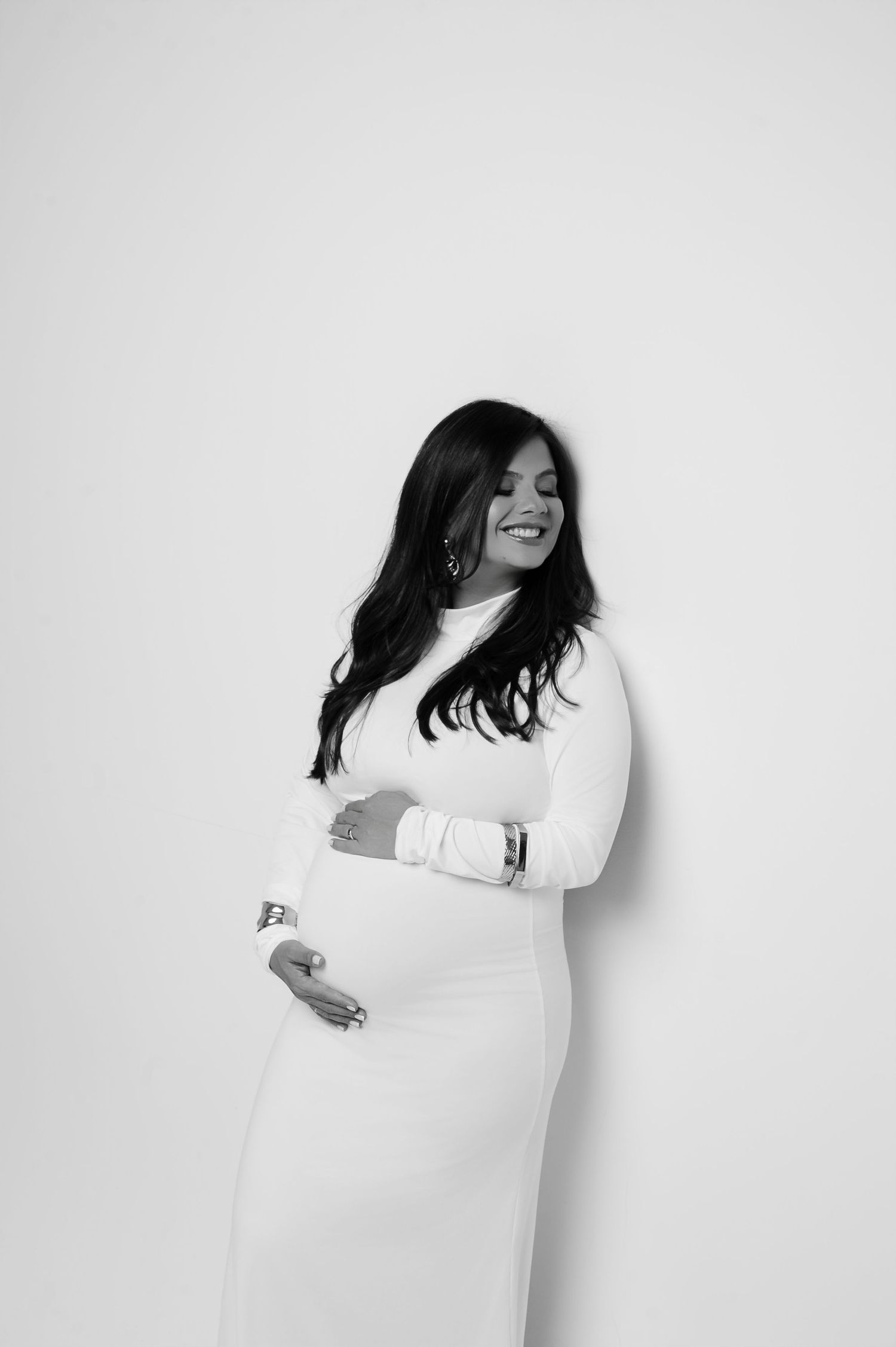 Retrato de gestante em estúdio usando vestido branco e de olhos fechados