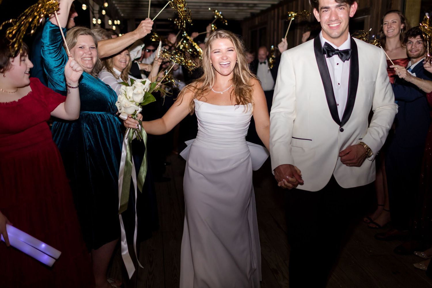 Wedding couple celebrates with guests during reception as they dance through a sparkler exit line.
