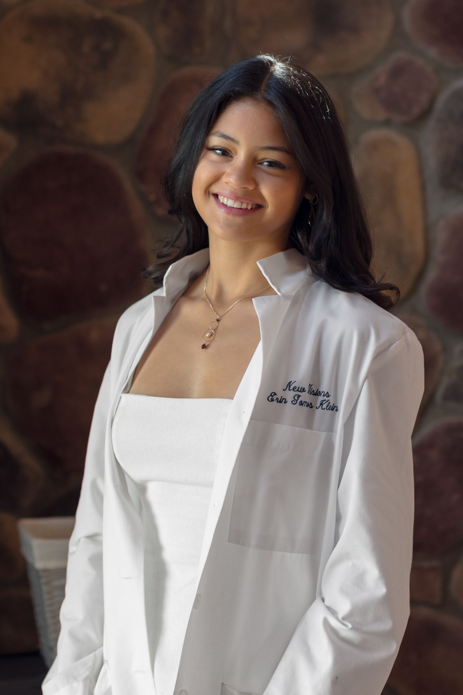 A graduate wearing a white medical coat and professional attire.
