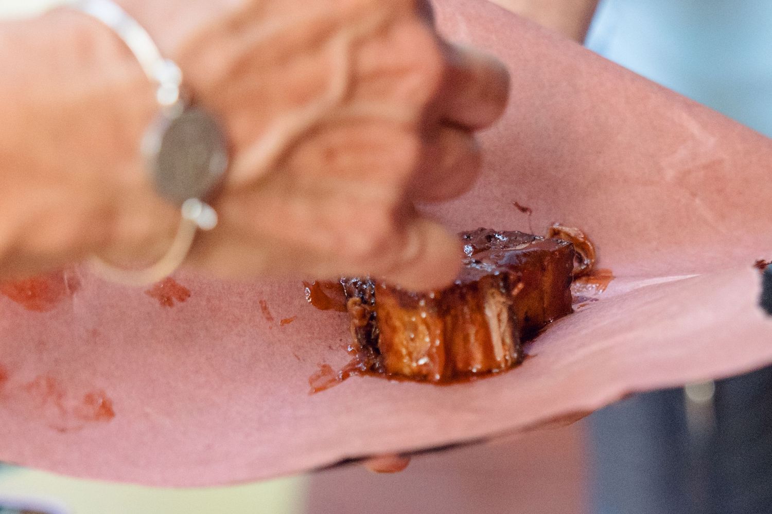 Close-up shot of BBQ meat being cut on pink butcher paper.