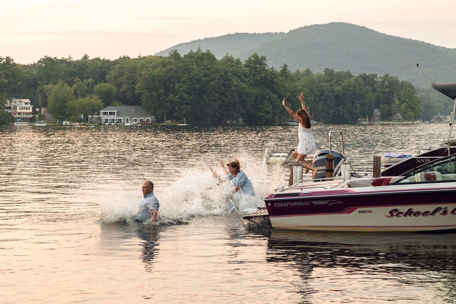 Water skiing action sequence on a lake with boats and mountains in the background.