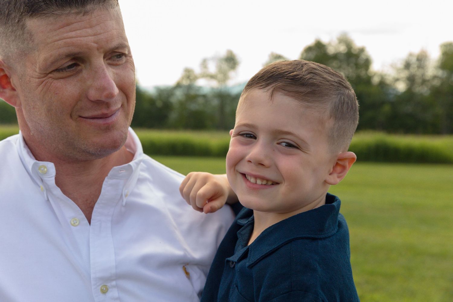 Casual outdoor family portraits taken in a sunny field.