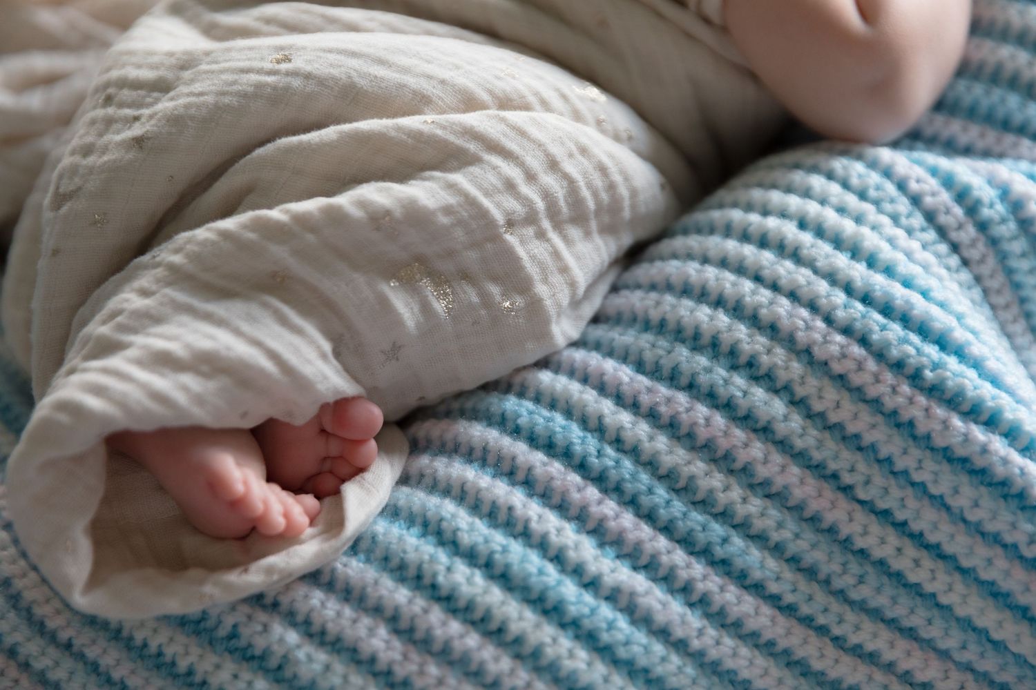 Close-up of tiny newborn feet resting on a blue and white striped blanket.