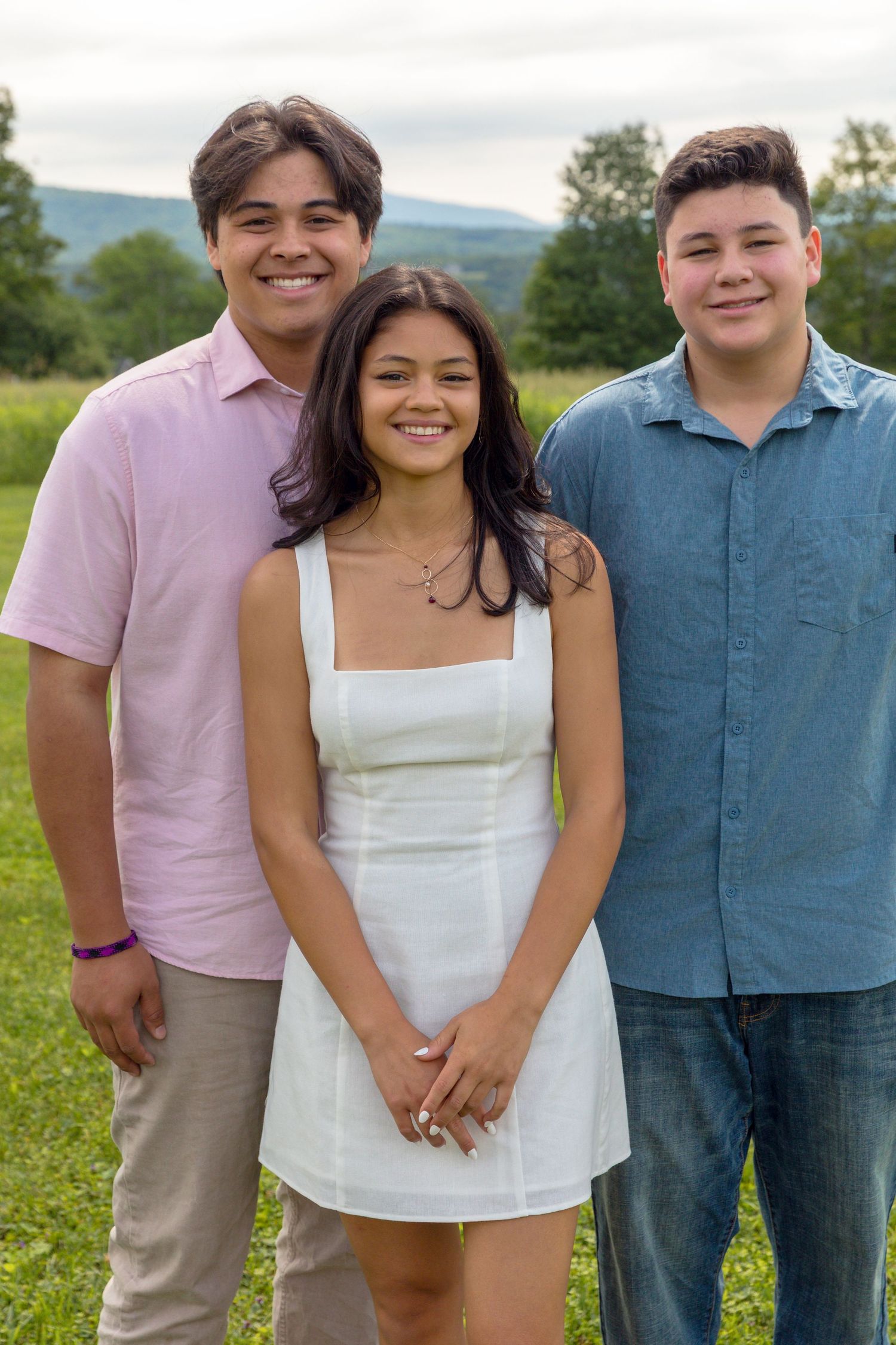 Family members pose together outdoors wearing coordinated summer outfits in pink, white and blue.