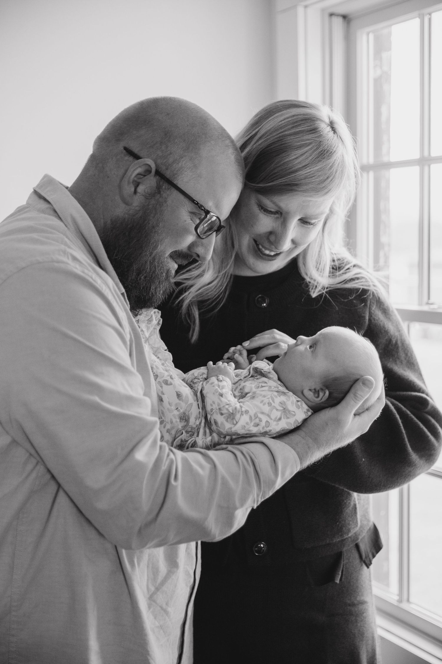 Black and white photo of family sharing tender moment by window.