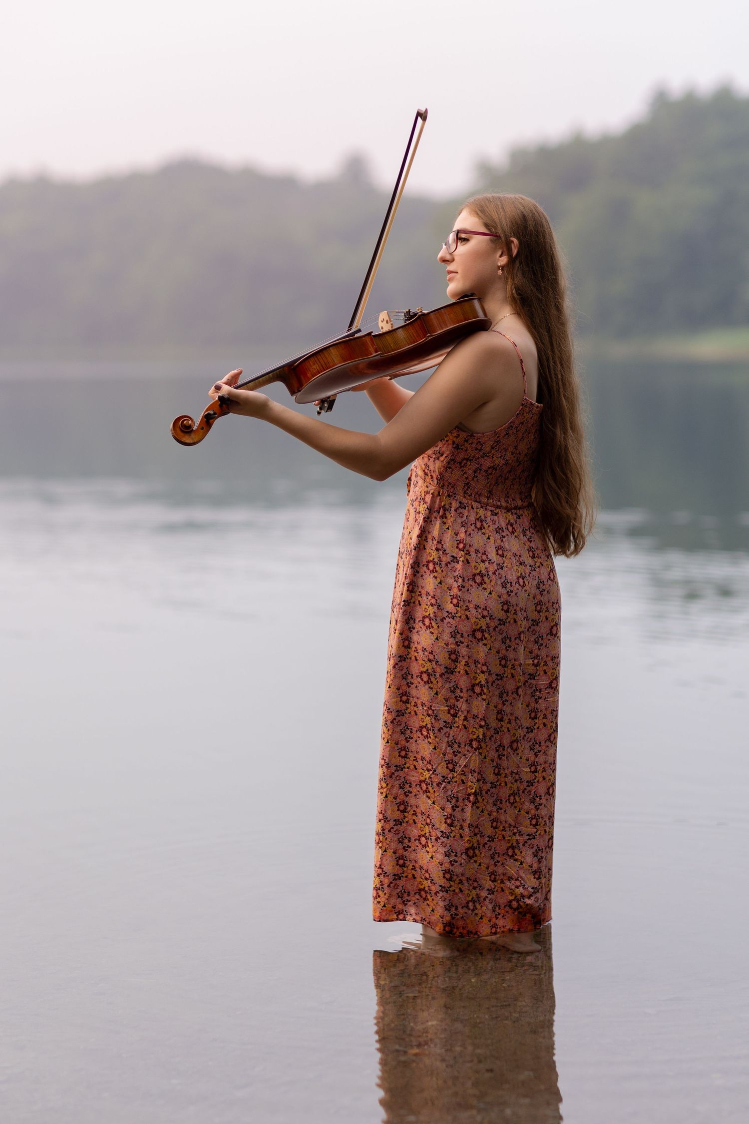 A violinist performs while standing in shallow lake waters.