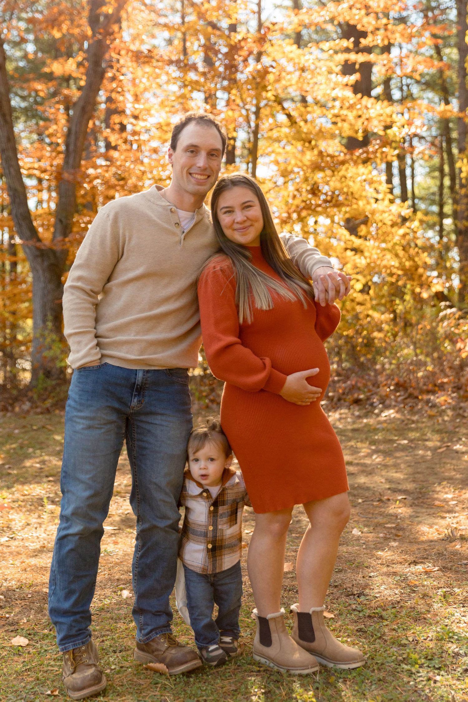 Family autumn photo shoot with warm sweaters against golden fall foliage.