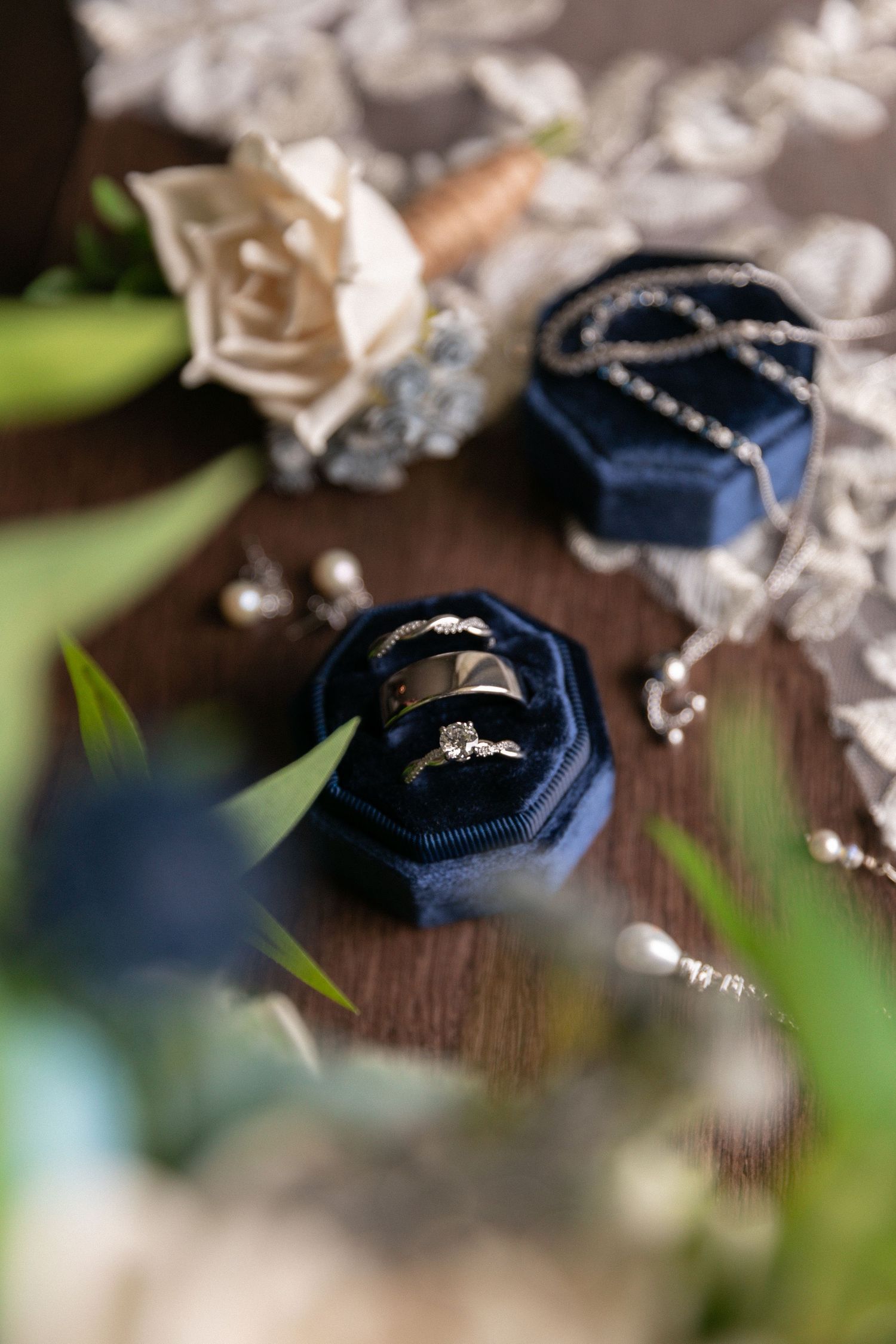 Close-up of navy blue ring box with wedding bands on wooden surface.
