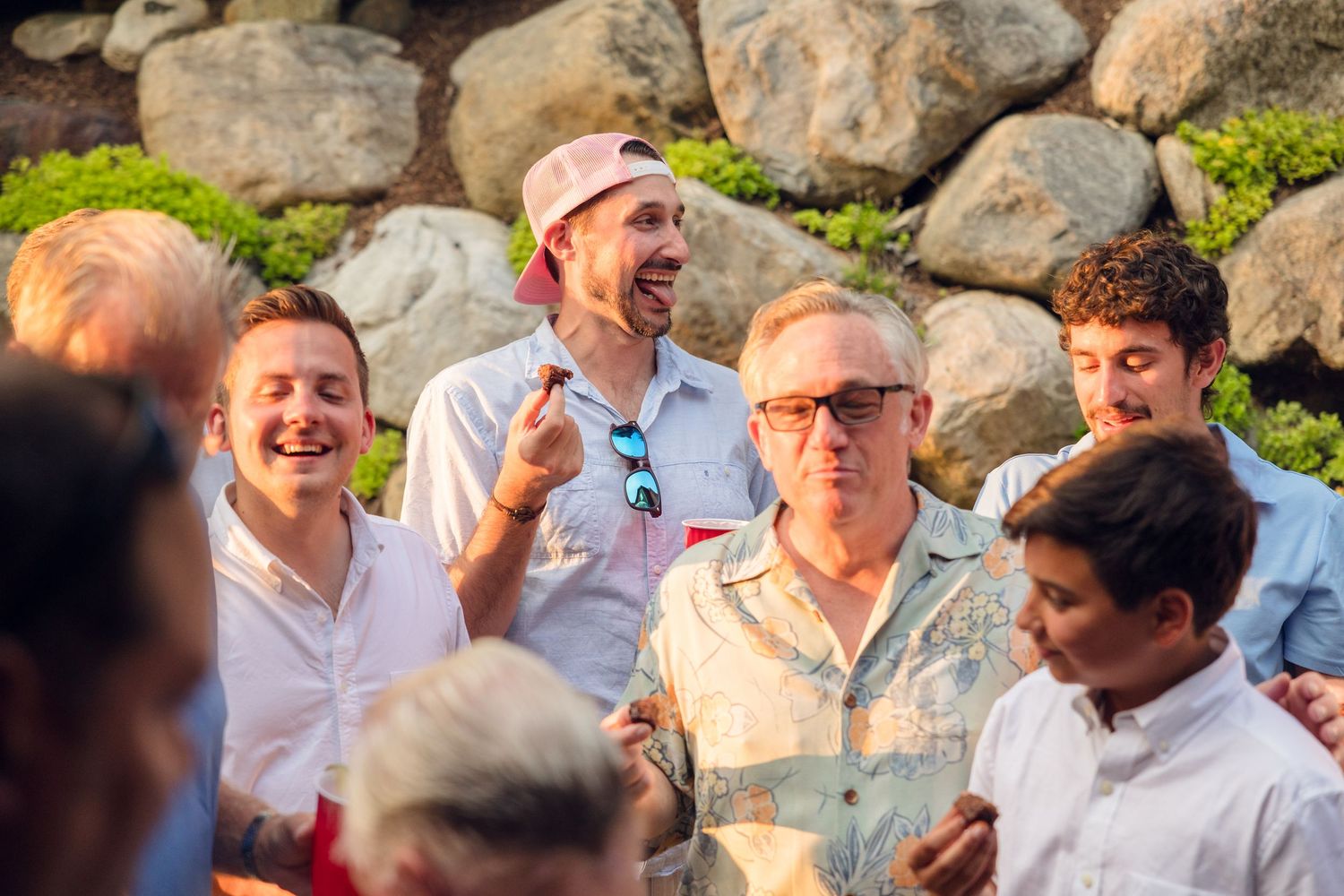 A large group of people gathered outdoors on a sunny day, smiling and laughing together.