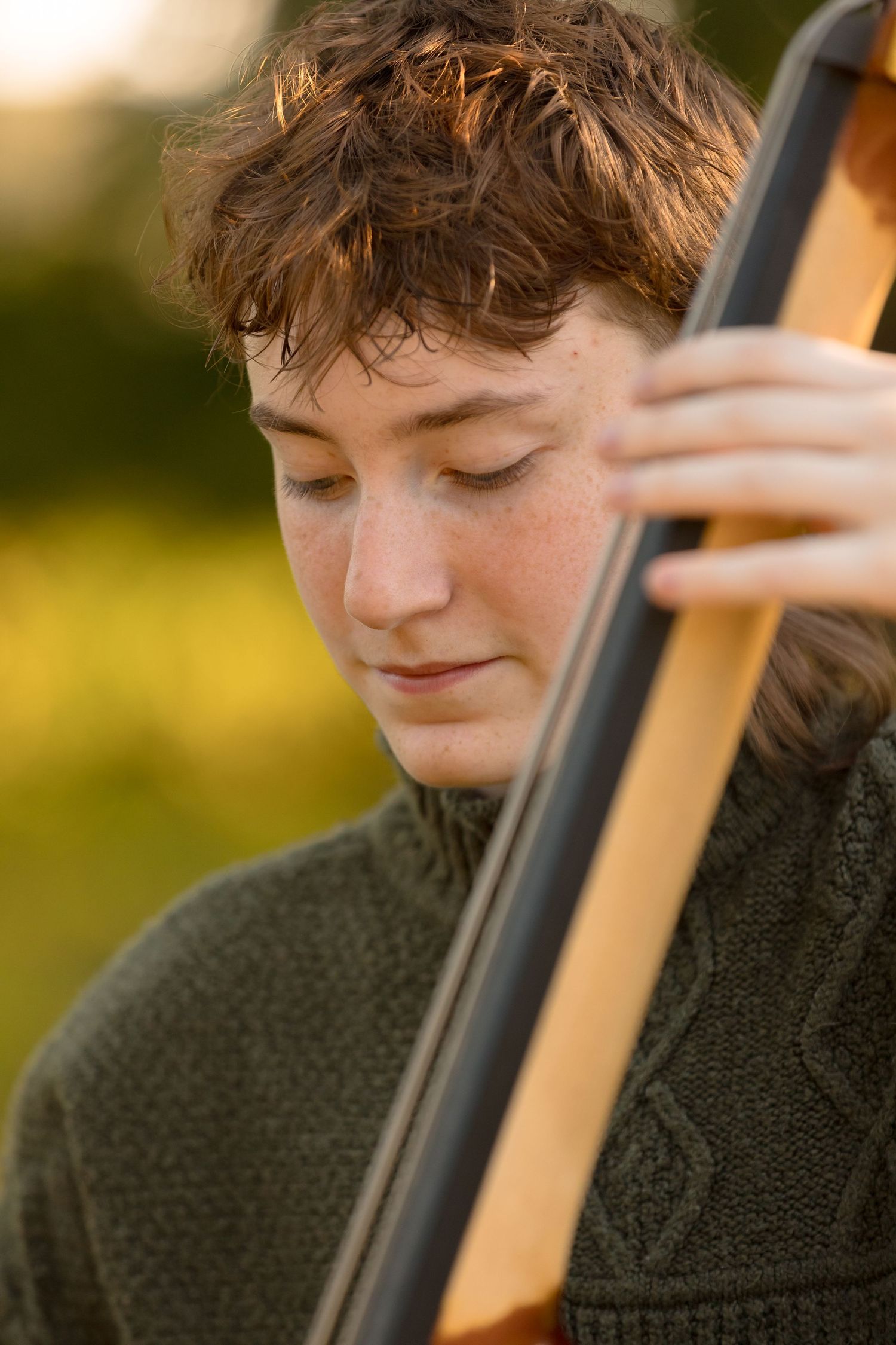 Close up shot of someone playing a wooden string instrument in warm lighting.