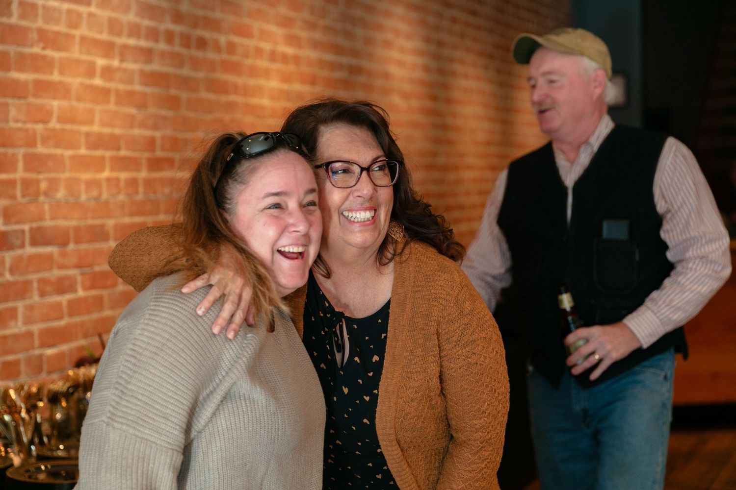 Candid moments of people sharing laughs in front of exposed brick wall.