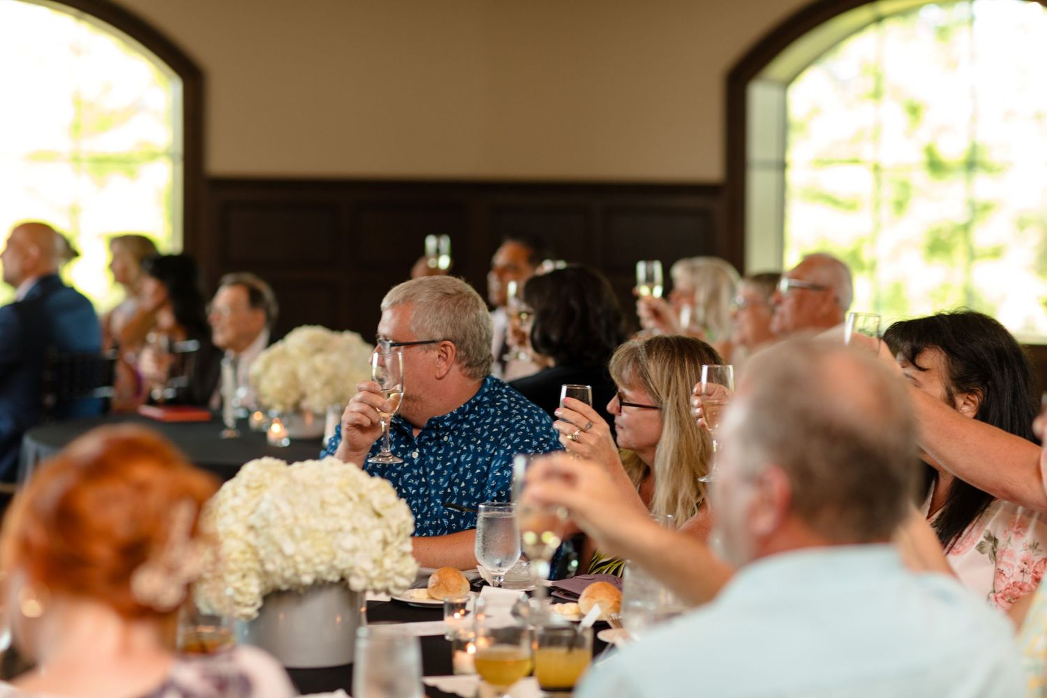 Guests seated at round tables during an elegant indoor celebration.