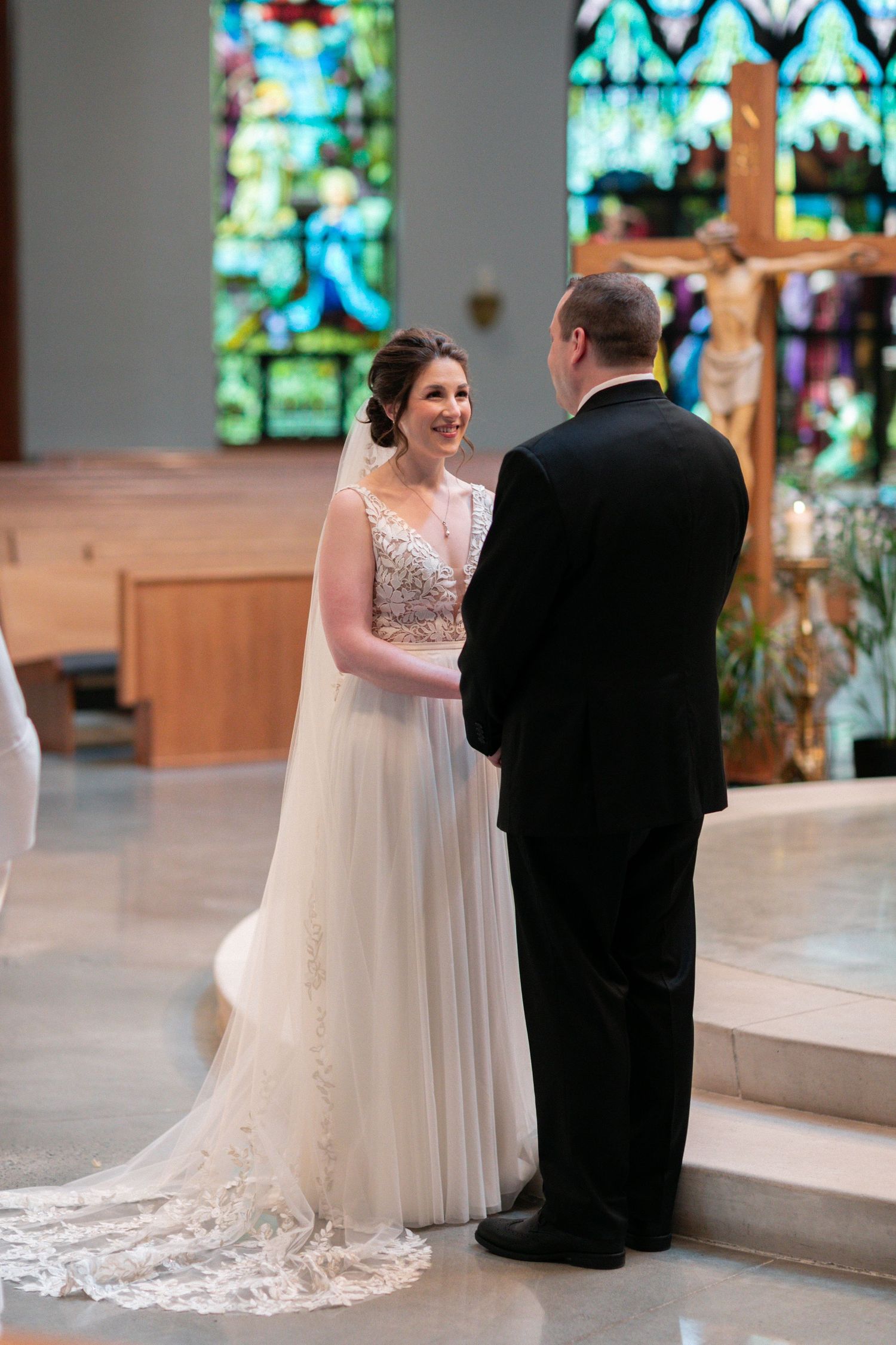 A wedding ceremony taking place in a church with beautiful stained glass windows and decorative elements.