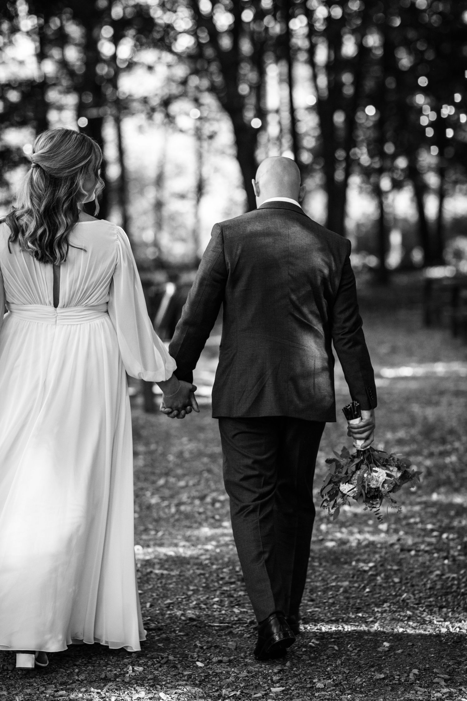 Black and white photos of a couple walking together through a wooded area.