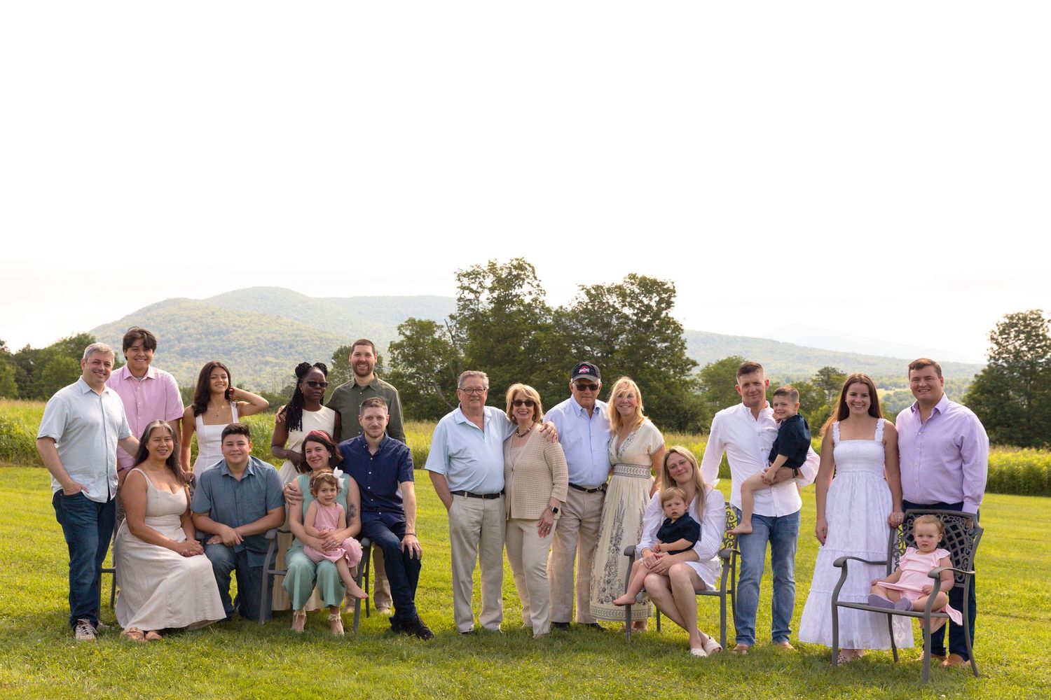 Large group photo of wedding guests posed together on a grassy hillside.