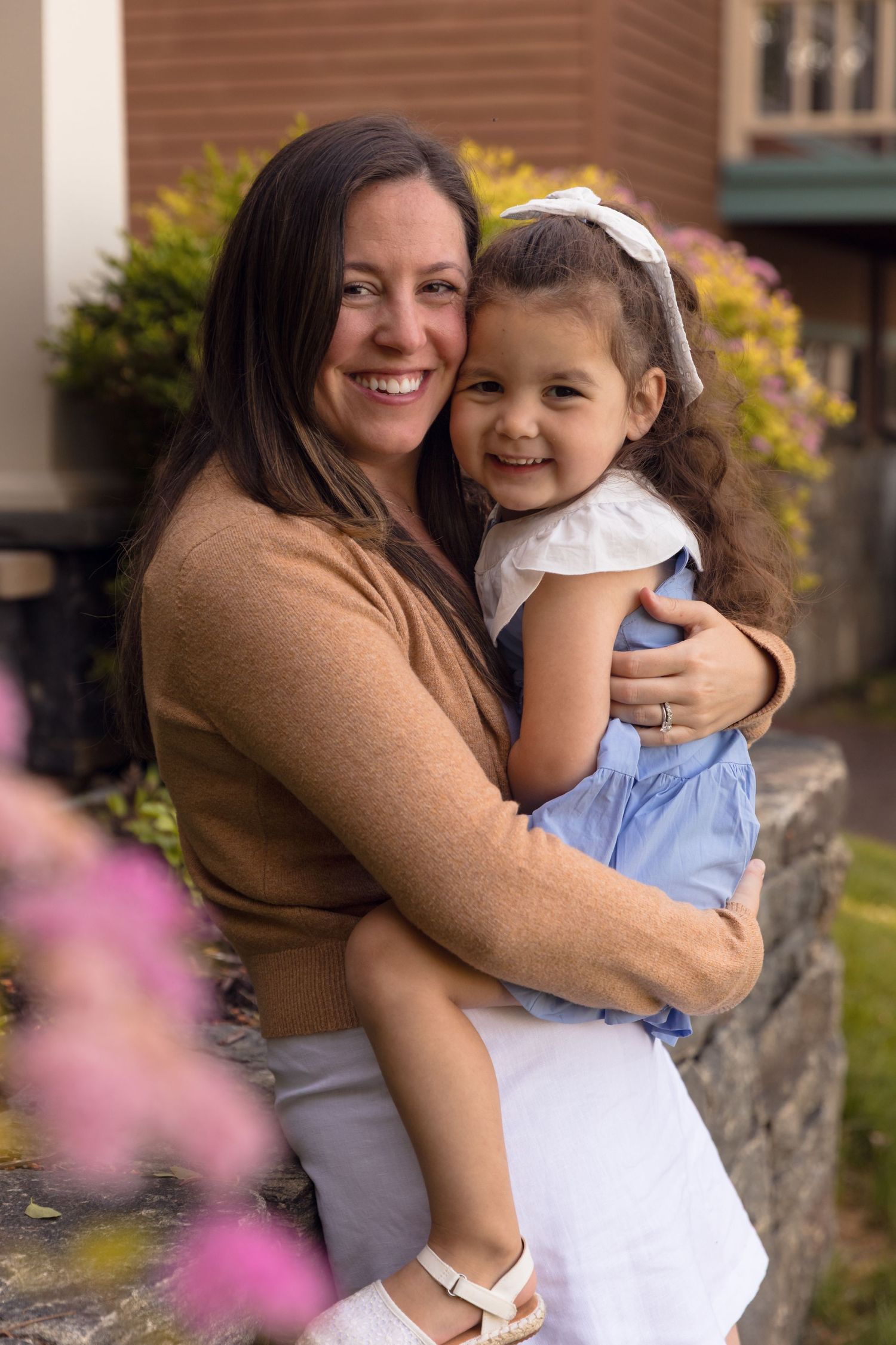 Mother and child sharing joyful embraces in outdoor garden setting.
