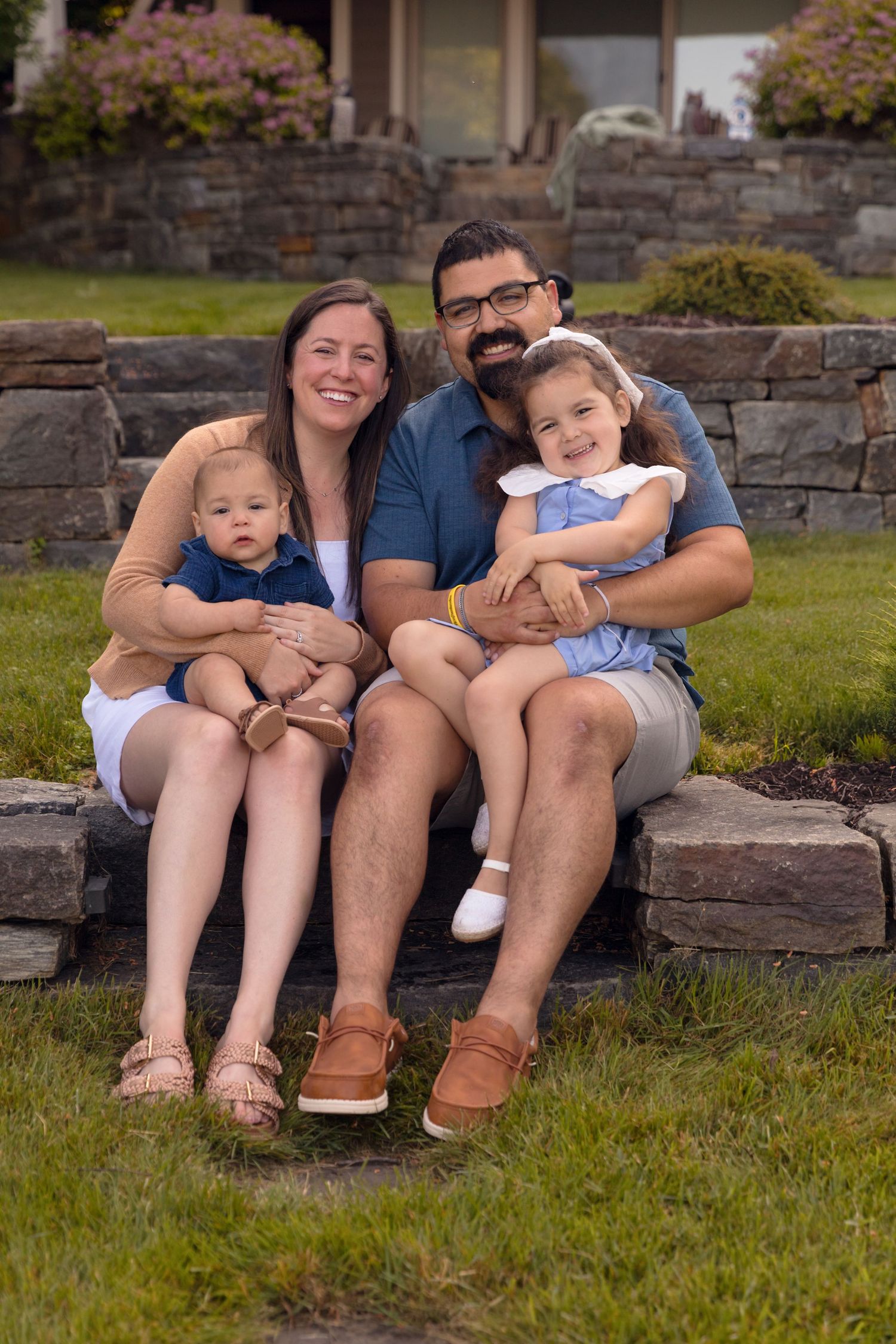 Family relaxing together on stone steps in a garden setting.