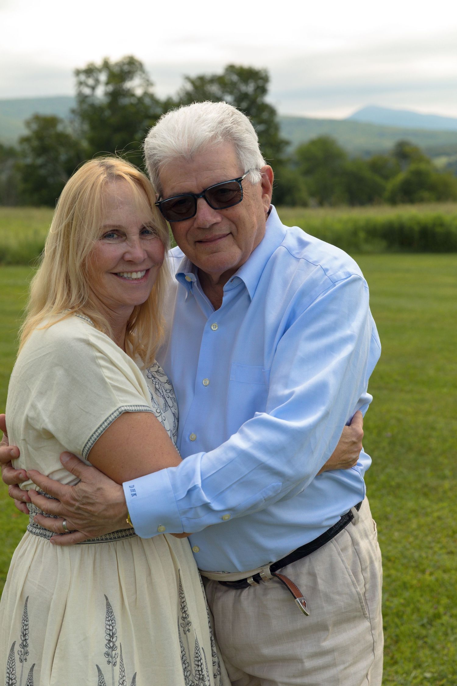 Loving embrace between two people in a sunny outdoor field.