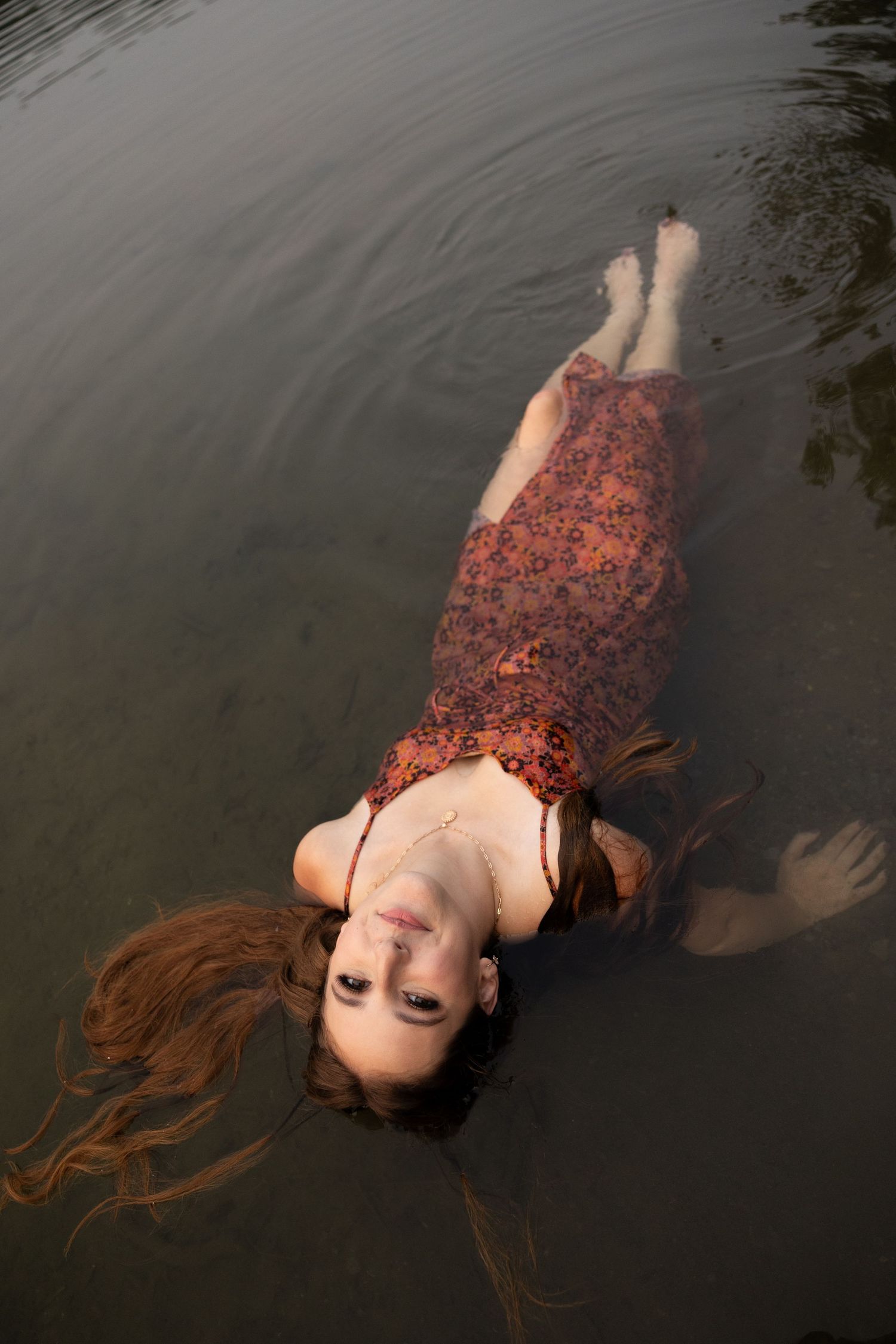 A floating pose creates an ethereal effect in dark lake waters.