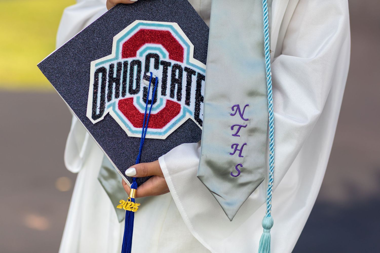 Close up of decorated graduation cap with Ohio State University logo and blue tassel.